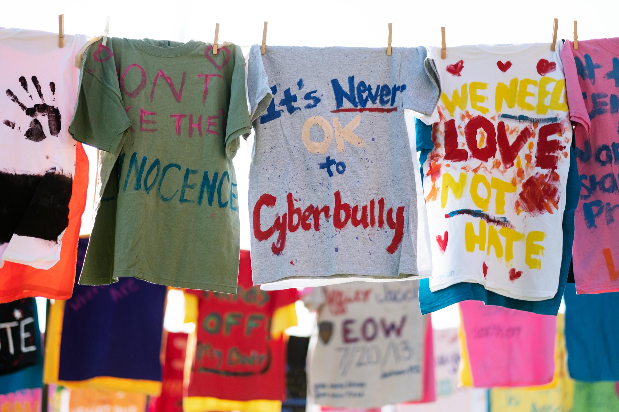 A colorful array of painted t-shirts hang by clothespins as part of the Clothesline Project.