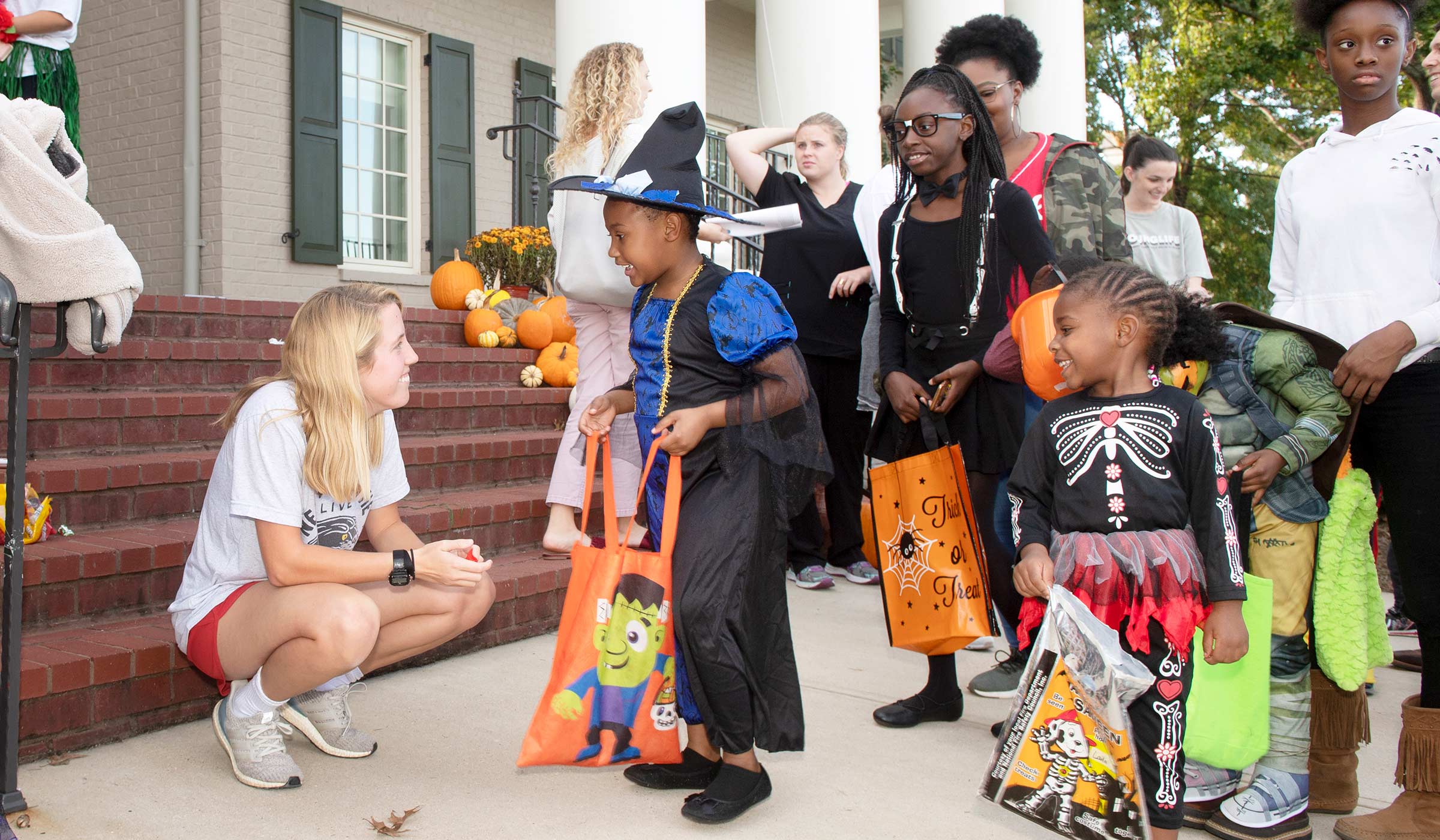 Kids dressed in Halloween costumes trick or treating in front of Chi Omega