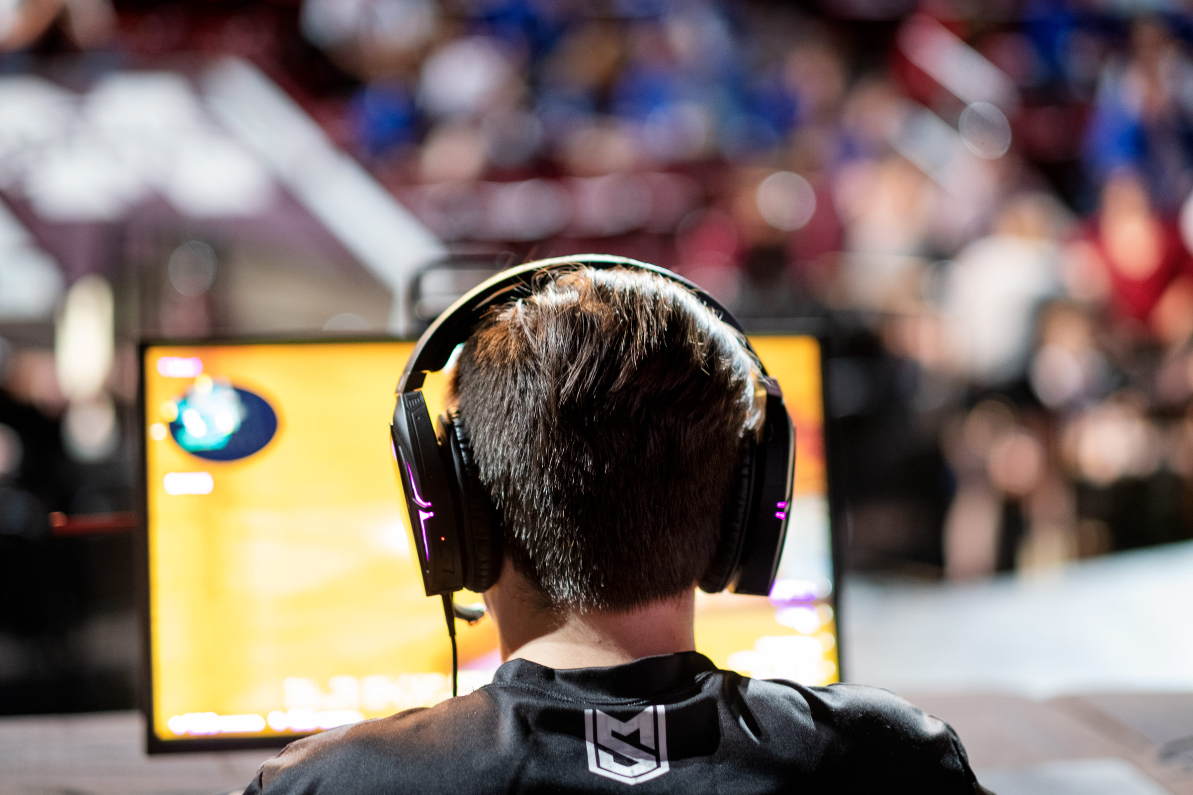 Wearing headphones and framed by the glow of a yellow computer screen, an MSU student eSports team member competes at the Hump.