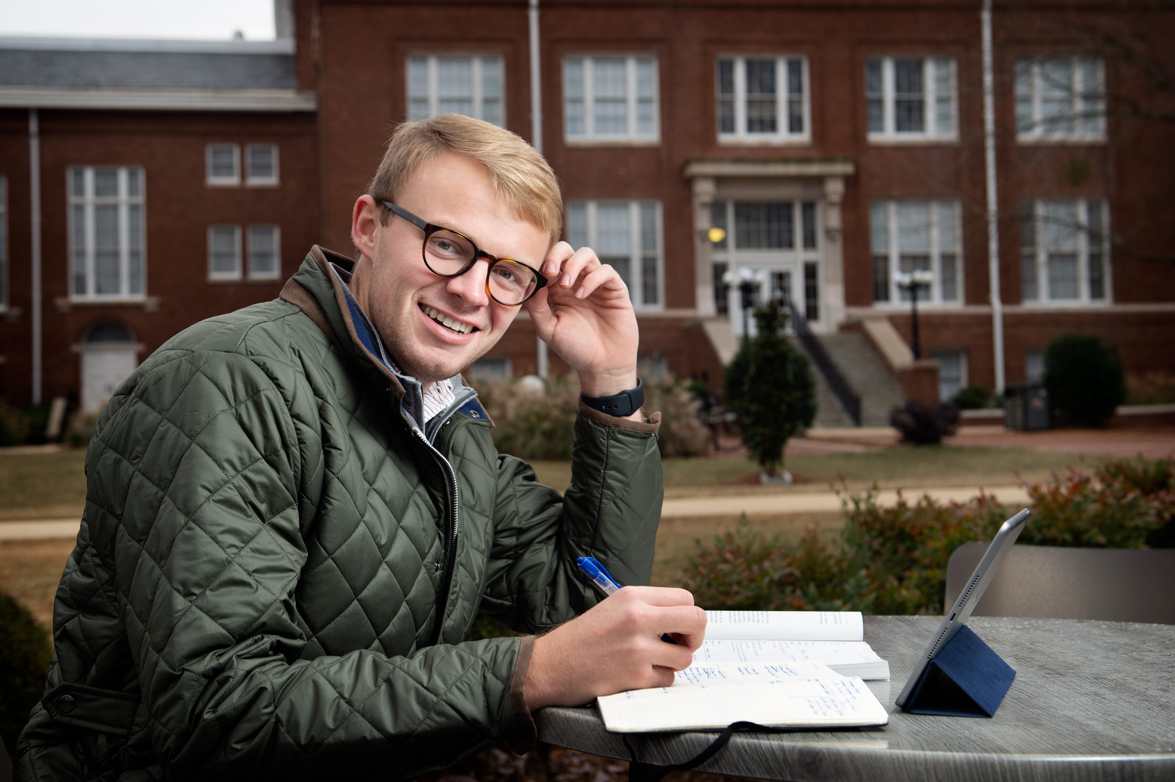 Reid Stevens, pictured at a table in front of Colvard Student Union with Lee Hall in the background