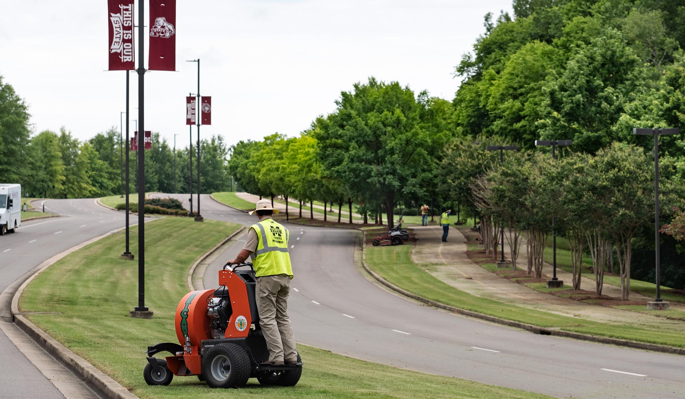 With a worker tending to the grass in the cneter median, MSU&#039;s landscape crew works to maintain MSU&#039;s North Entrance Drive..