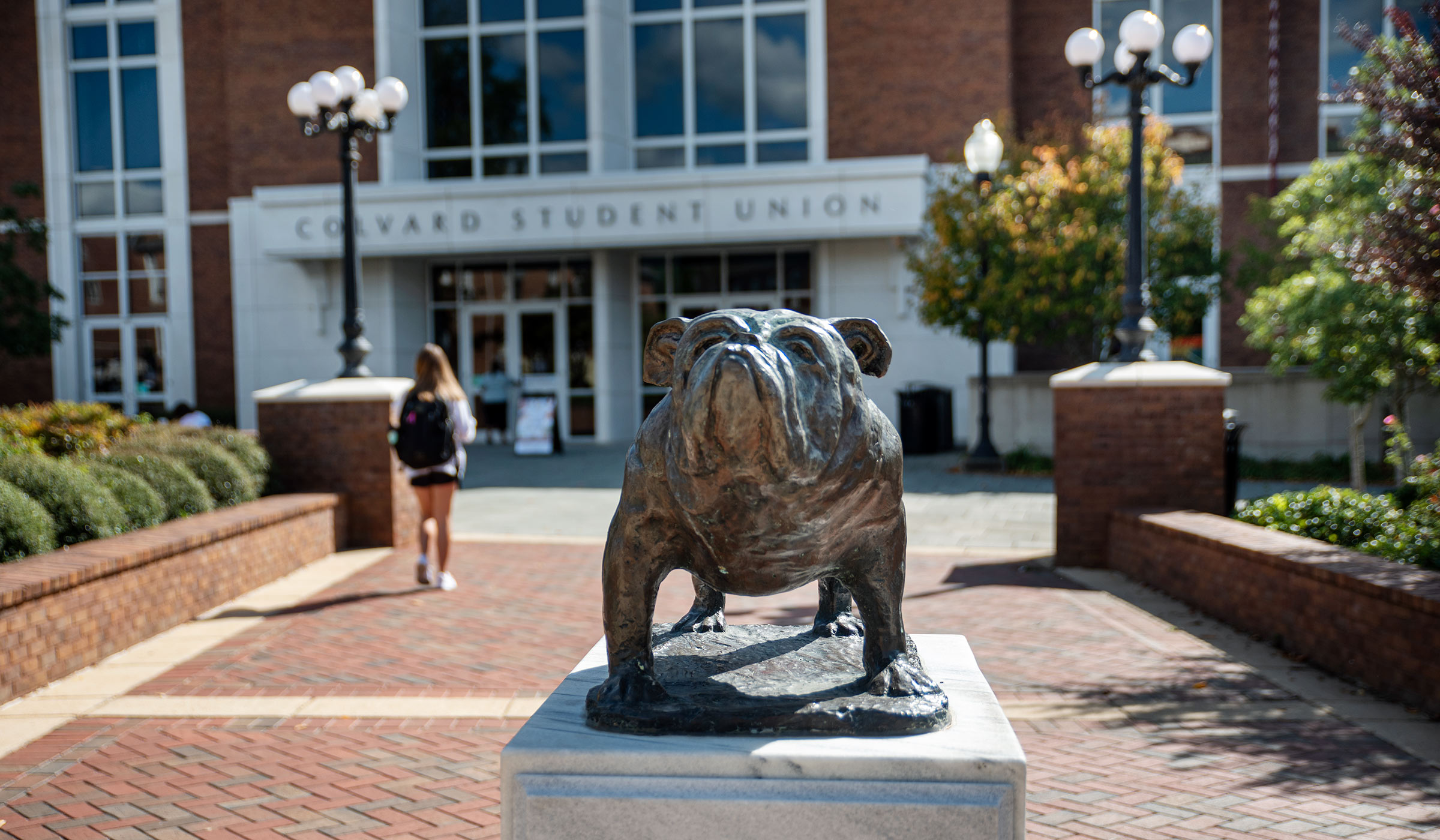 Bulldog statue in front of Student Union with student walking past in background.
