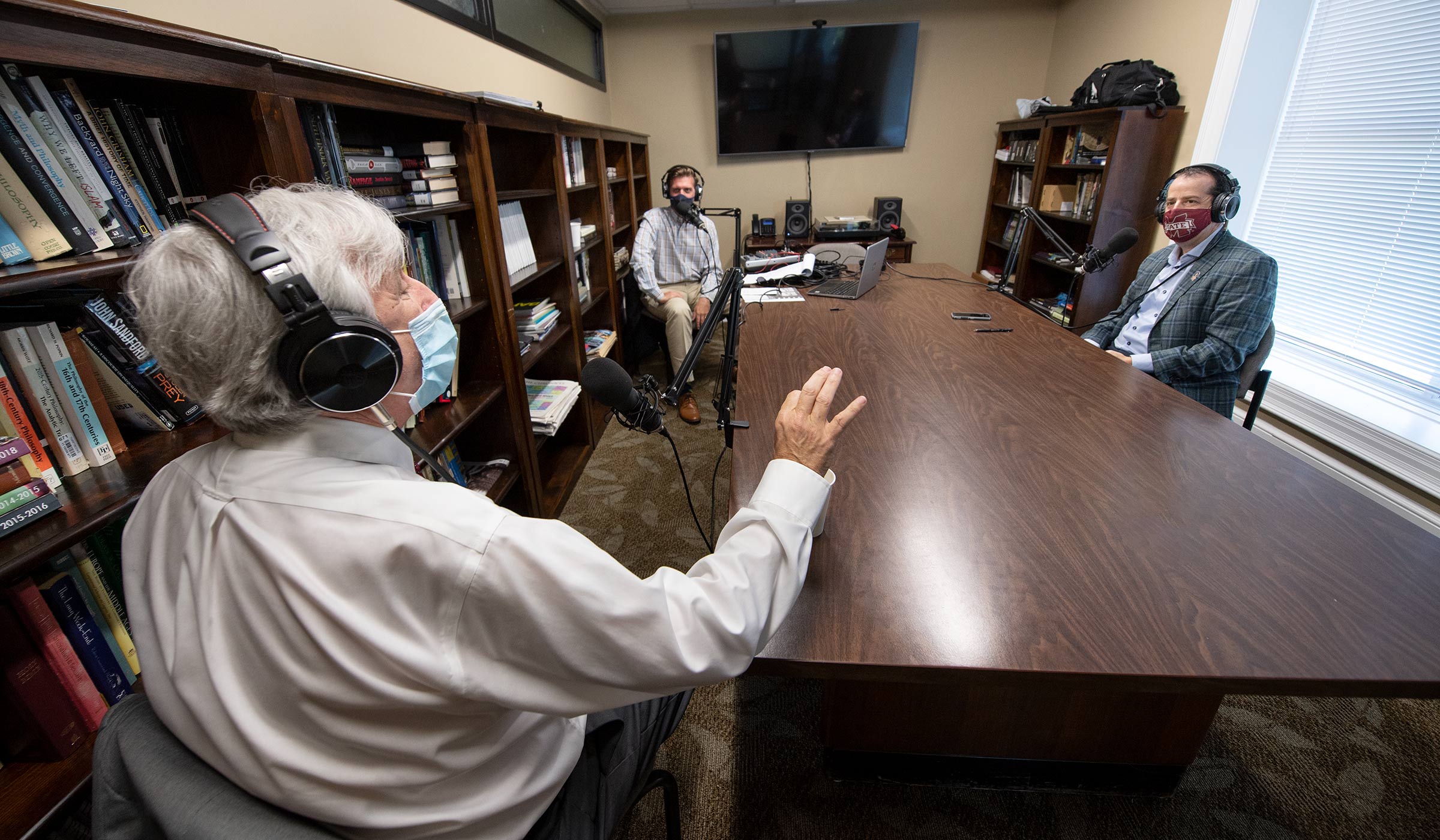 With all three wearing headphones and face masks, Astronaut Scholar Program representative Ray Gildea speaks with across a table with honors Professor David Hoffman and Wade Leonard for an Honors podcast.