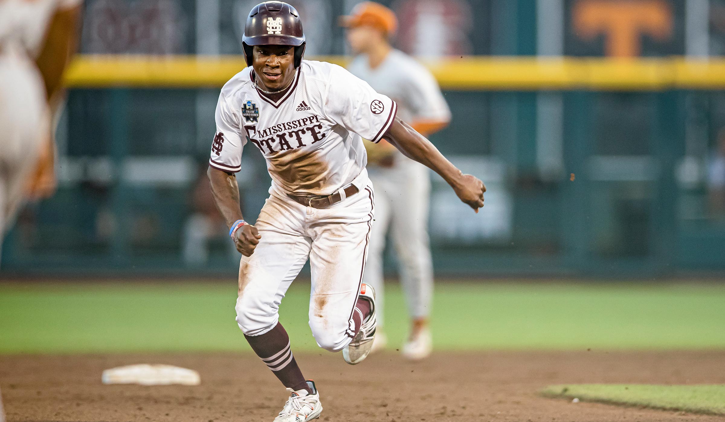 Man in white baseball uniform covered in dirt and maroon helmet running