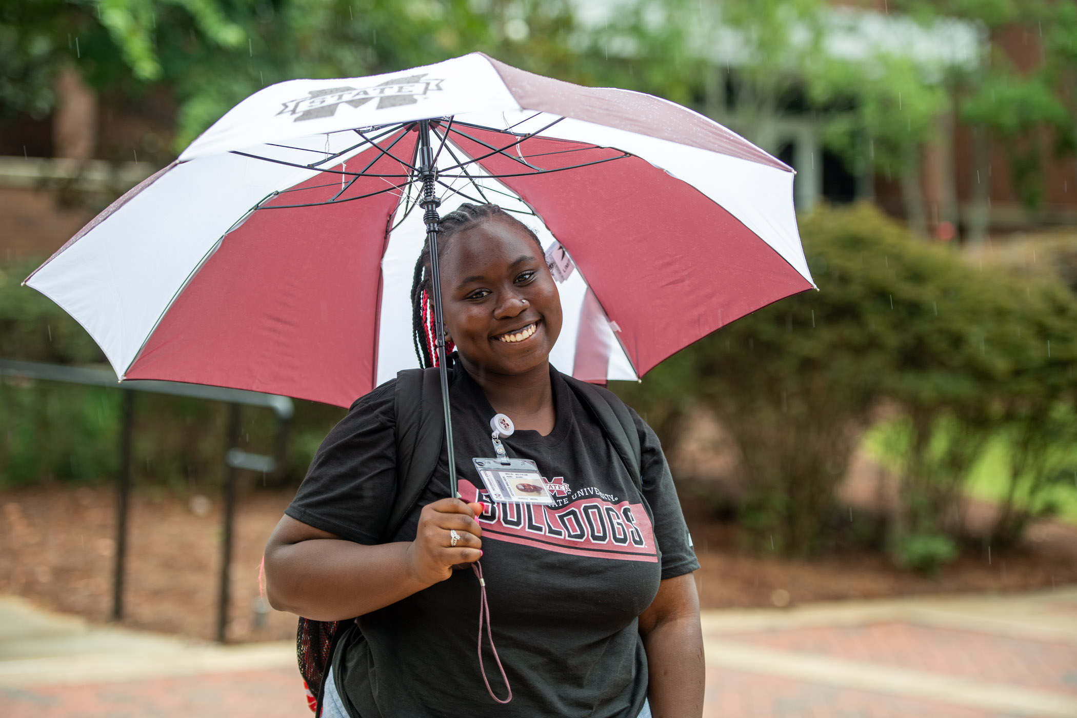 Smiling student, Joyous Walker, sports a large MSU umbrella with cheer despite a rainy first day back on campus