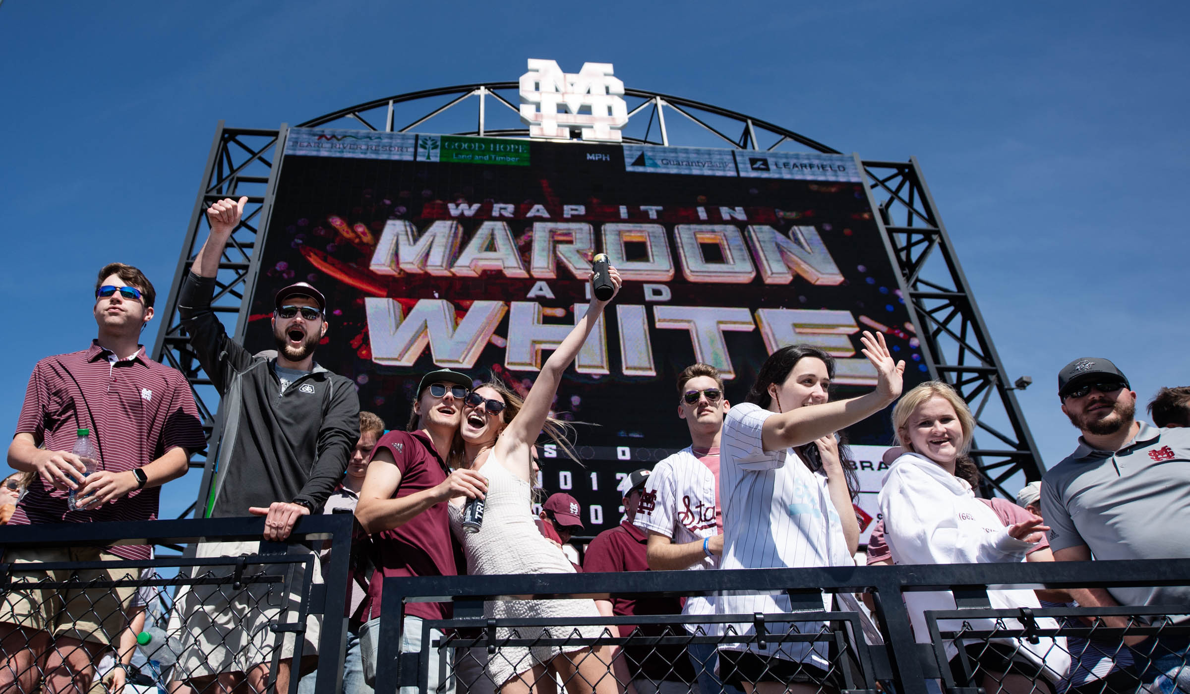 With &quot;Wrap it in Maroon and White&quot; on the Dudy Noble Scoreboard behind them, baseball fans cheer and celebrate in Left Field Lounge at the conclusion of the series against Ole Miss.