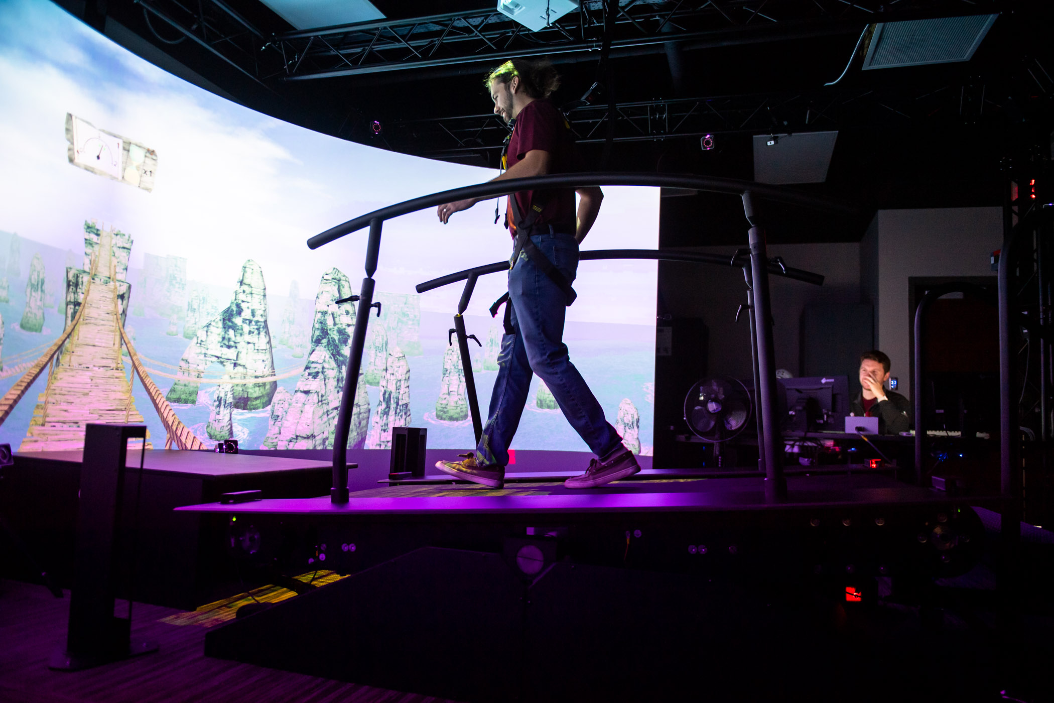 A man walks on a treadmill surrounded by an immersive screen
