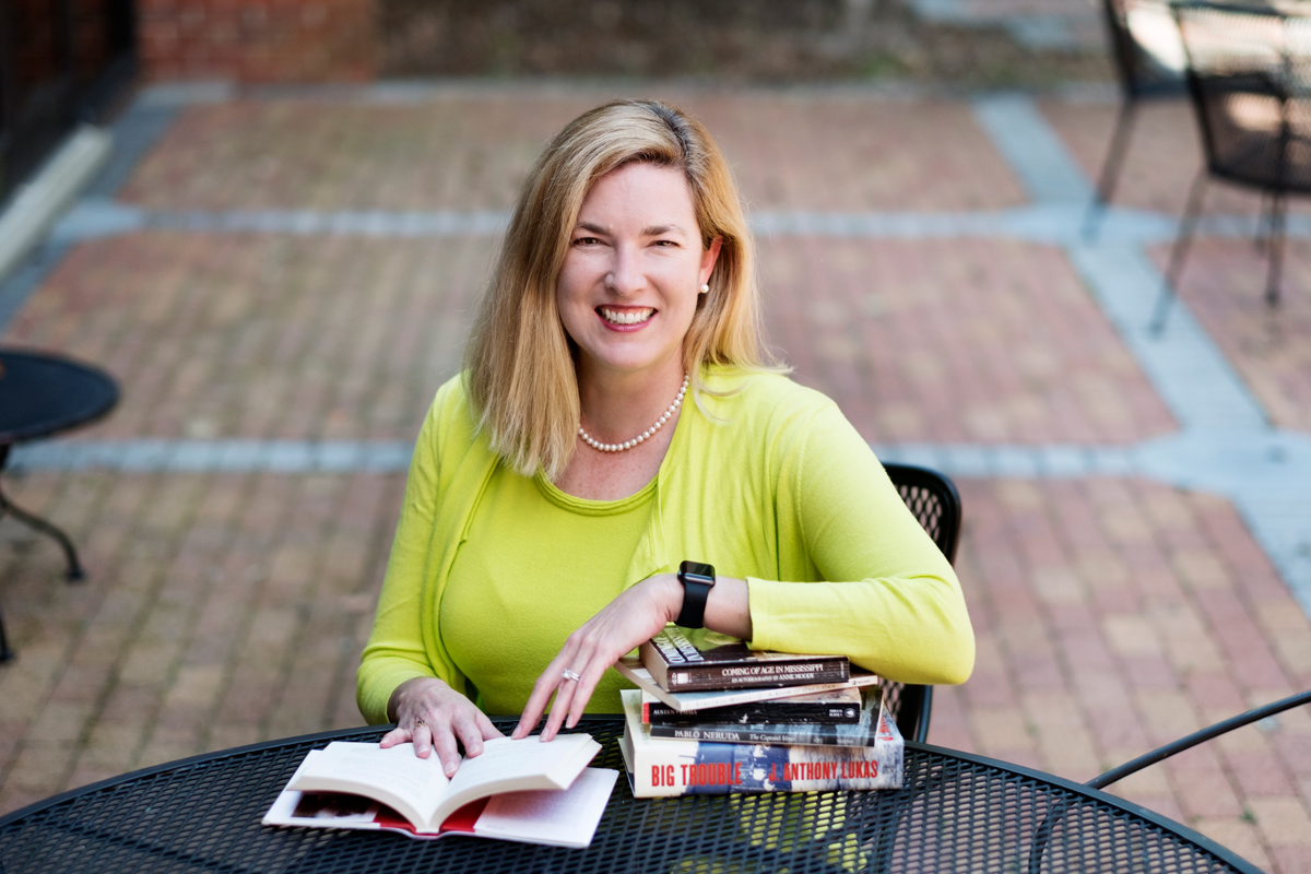 Marian Montgomery Chancellor, pictured sitting at a patio table with a stack of books.