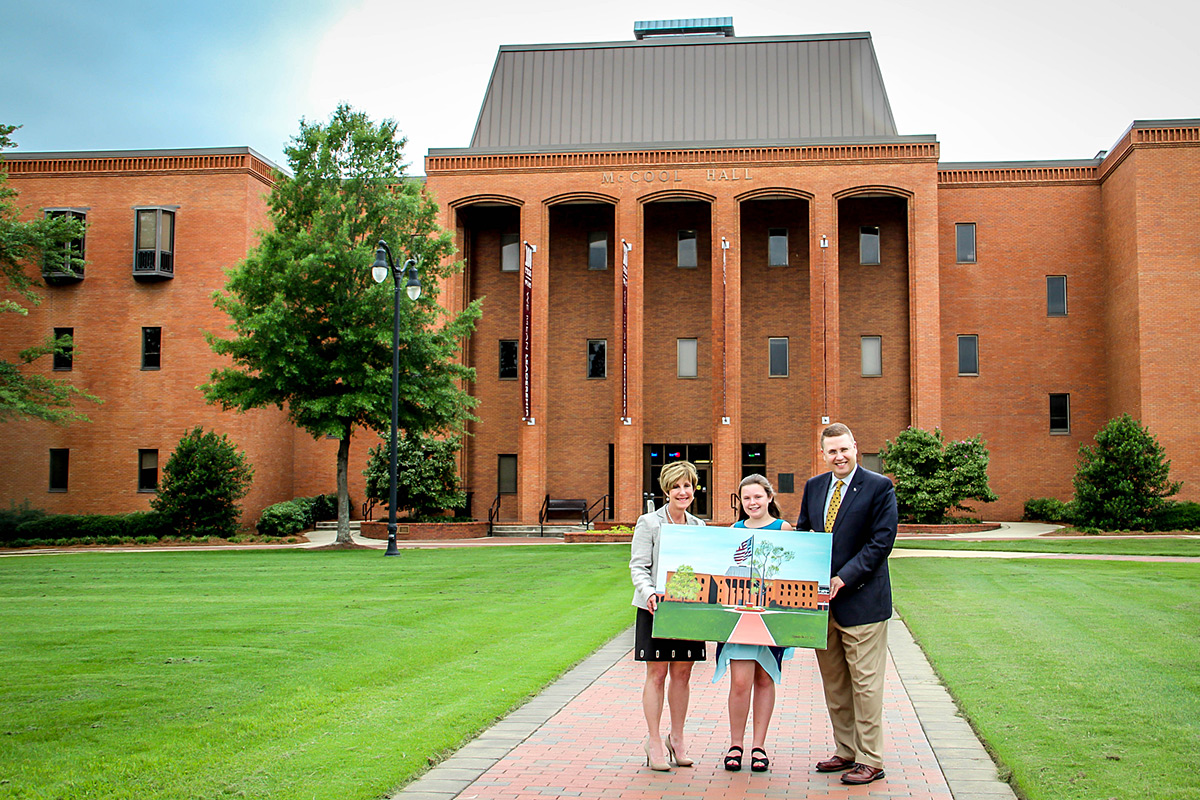 Anna Davis presents her McCool Hall painting to Dr. Mike Highfield and Dr. Sharon Oswald.