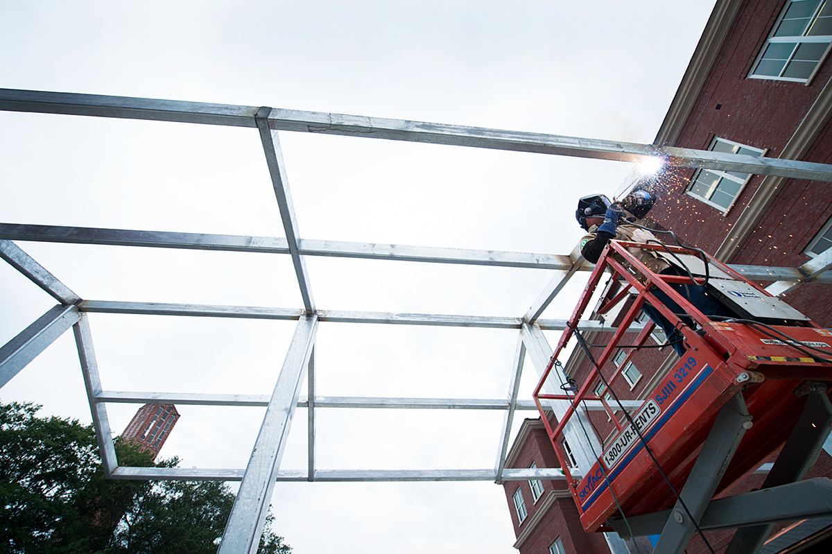 Travis Galliano welds beams for an awning at the new Old Main Academic Center