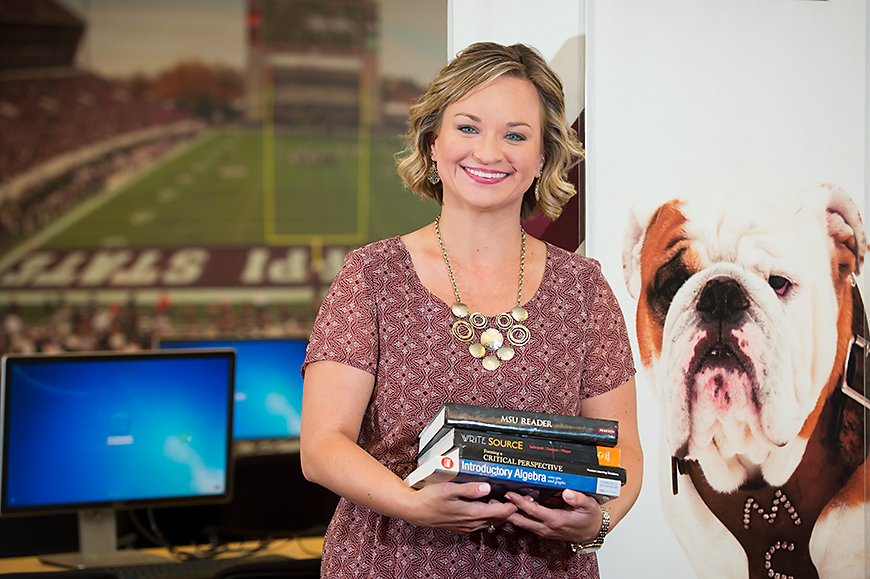 Erica Smith holds a stack of books while smiling.