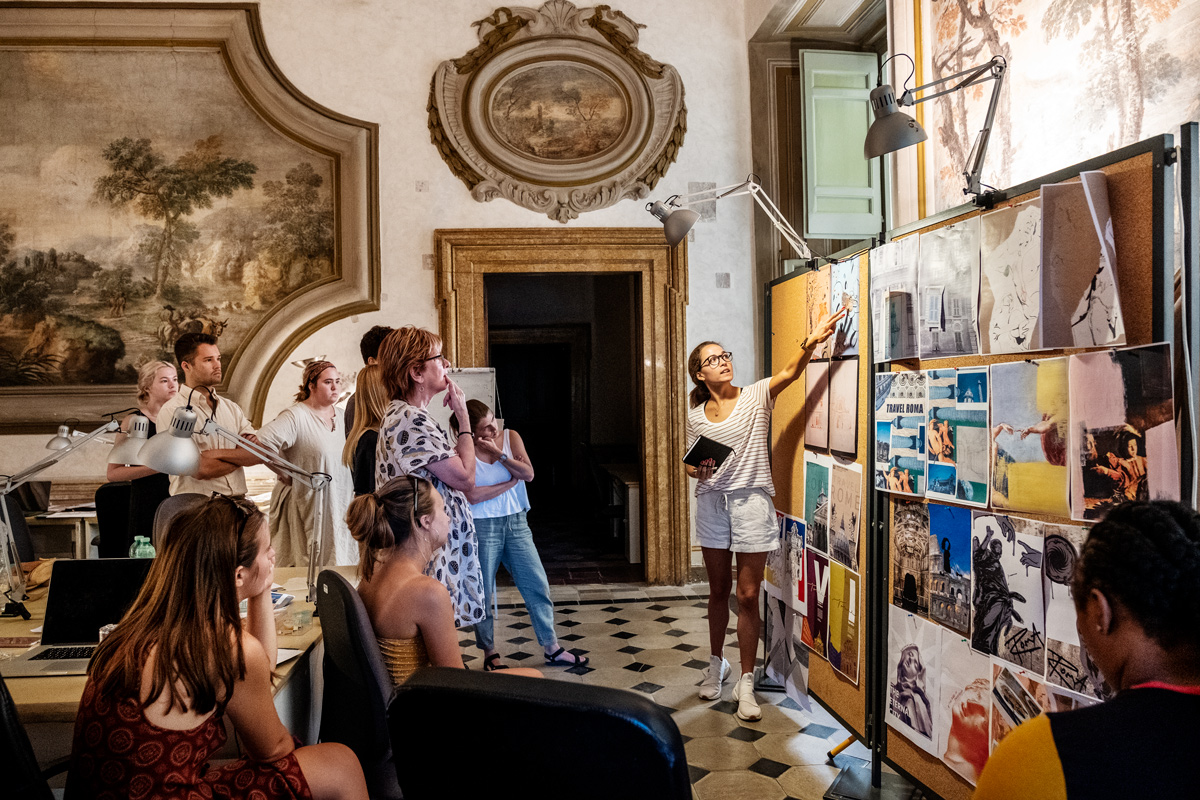 Surrounded by 16th Century decorations on the palace walls of their Rome art studio, CAAD students critique their poster designs