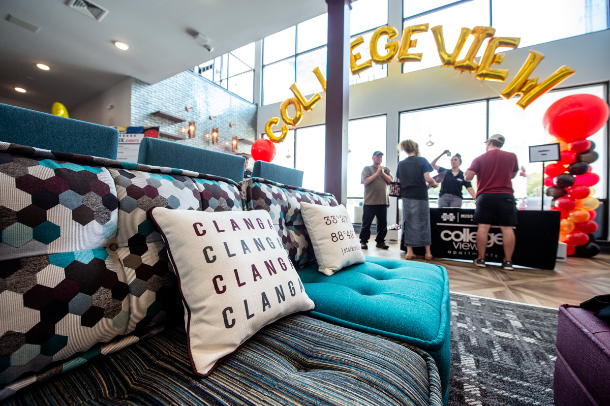 Newly arrived residents check in to College View student housing under balloons and with a Clanga pillow and couch in foreground