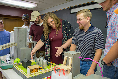 Kelley Wamsley, center, talks with poultry science students about a feed mill model constructed for her course. Pictured from left are Blake Campbell, Caleb Woods, Coleman Lay, Wamsley, Bryce Hollomon and Seth Walters. (Photo by David Ammon)