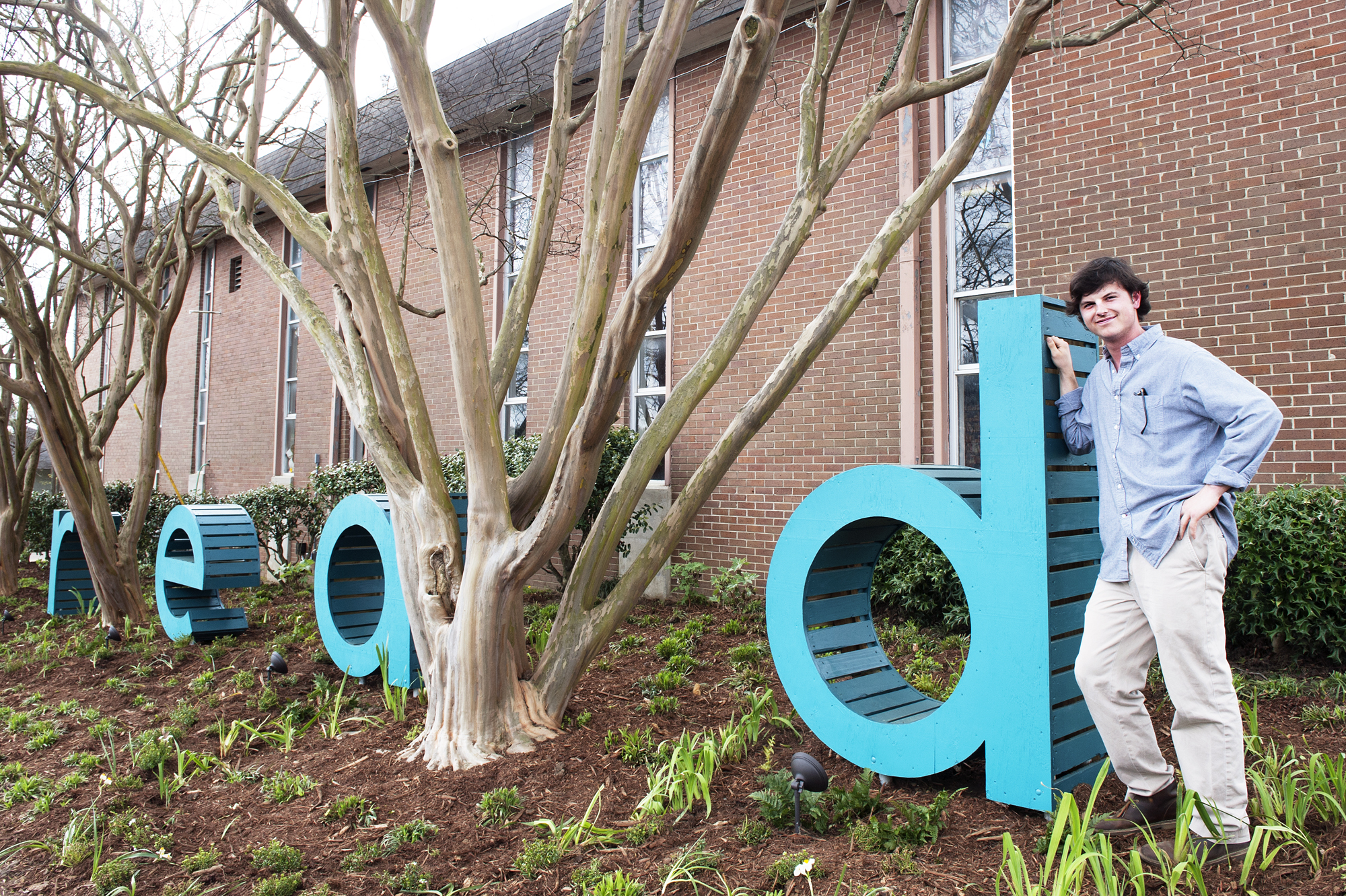 Mississippi State University senior landscape architecture major Travis R. Crabtree, a Dawn Brancheau Service-Learning Scholar, celebrates the unveiling of the new sign he designed for Starkville Public Library.