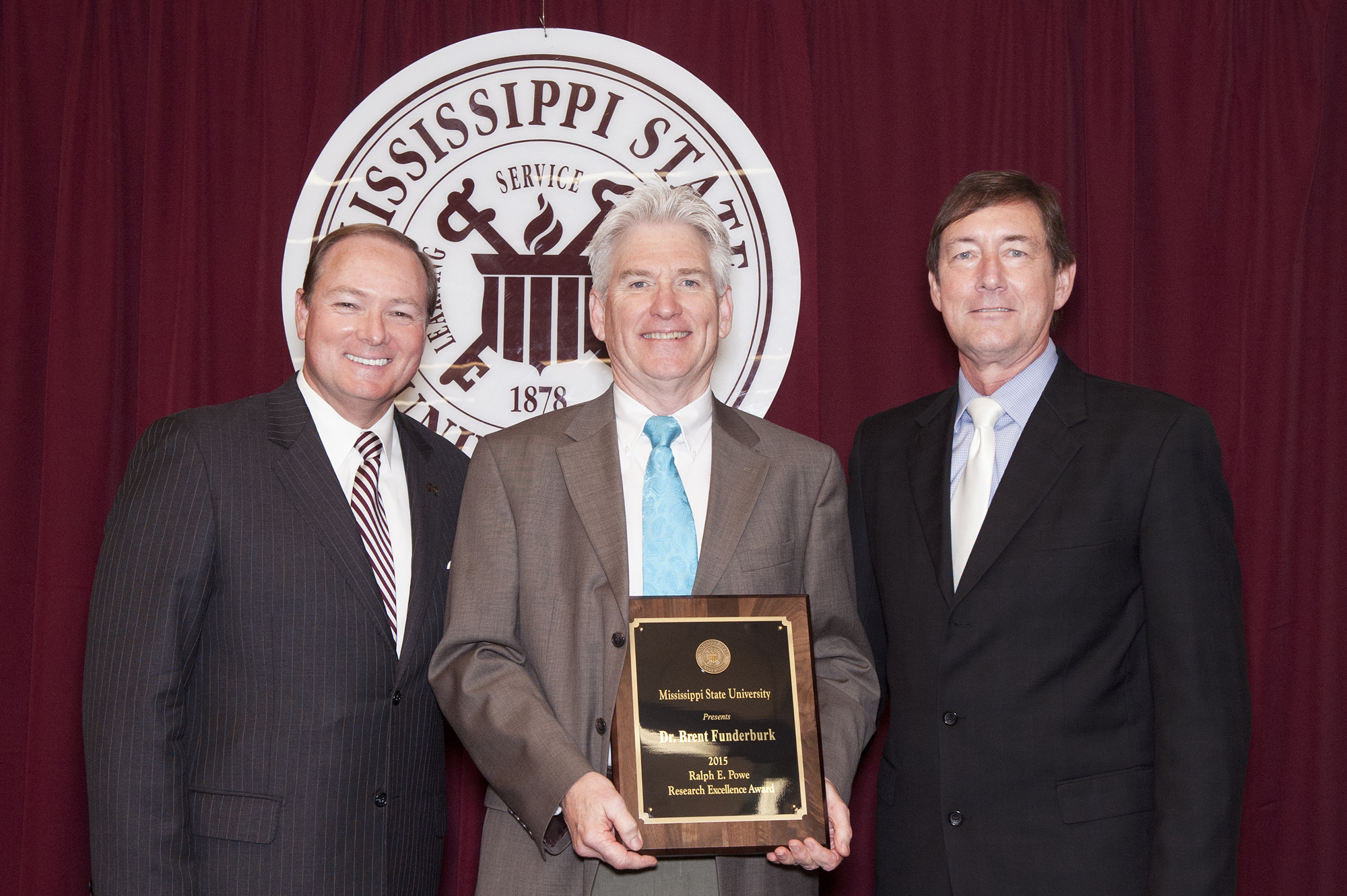 Mississippi State President Mark E. Keenum, left, and Greg Bohach, right, vice president for agriculture, forestry, and veterinary medicine, presented art professor Brent Funderburk with the 2015 Ralph E. Powe Research Excellence Award Thursday afternoon [April 30]. The Powe Award is the university's top research honor and is named for the late MSU alumnus and longtime research vice president.
