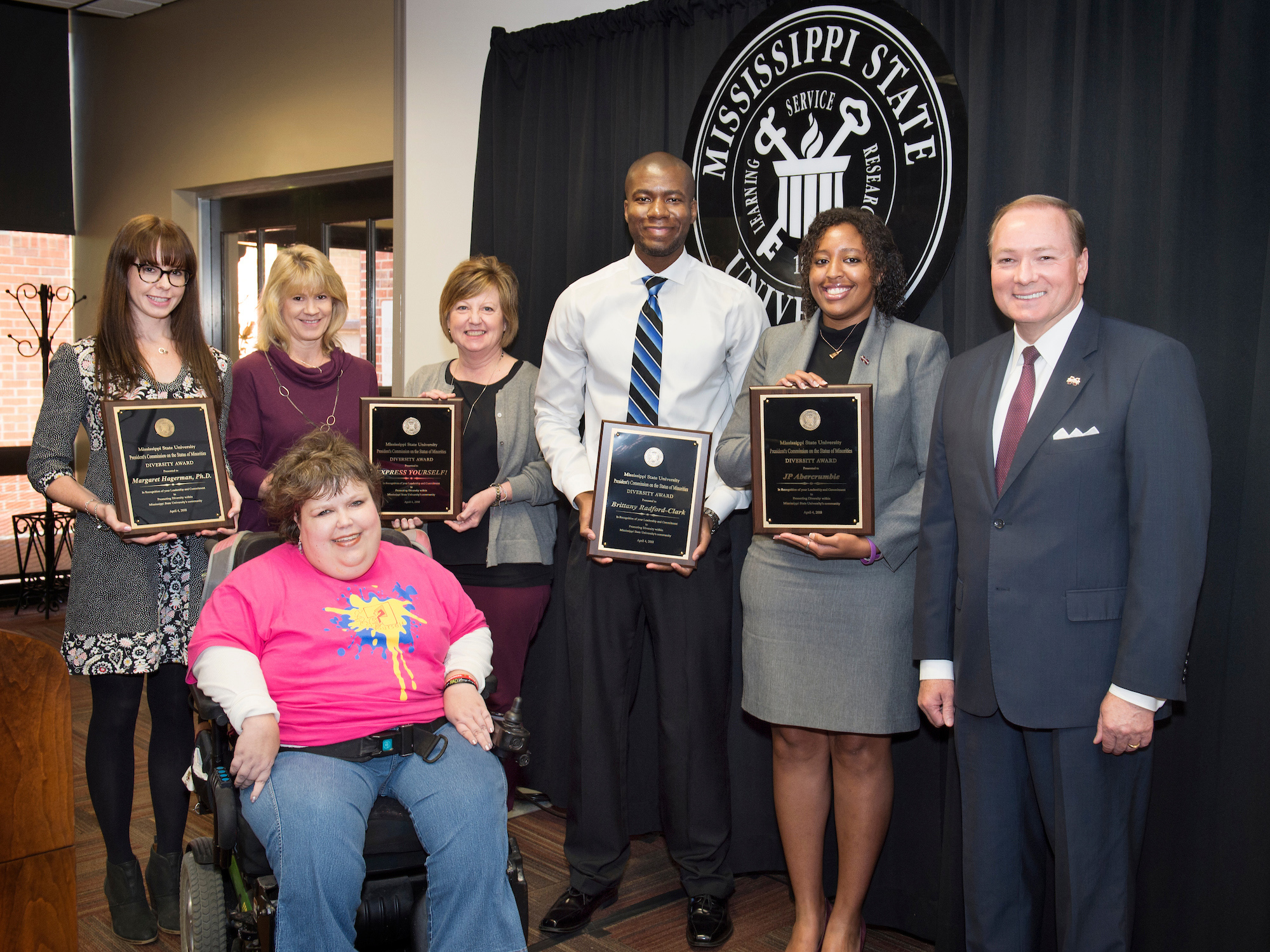 Mississippi State’s 2018 Diversity Award winners are EXPRESS Yourself! artist Candace Stephenson, pictured in front; back, from left, MSU Assistant Professor of Sociology Margaret A. Hagerman, EXPRESS Yourself! trackers Laurie Craig and Judy Duncan, David Clark (accepting on behalf of MSU graduate student Brittany Radford-Clark) and JP Abercrumbie, MSU assistant athletic director for life skills and community engagement. MSU President Mark E. Keenum, right, congratulated the honorees during an April 4 awards ceremony. (Photo by Megan Bean)