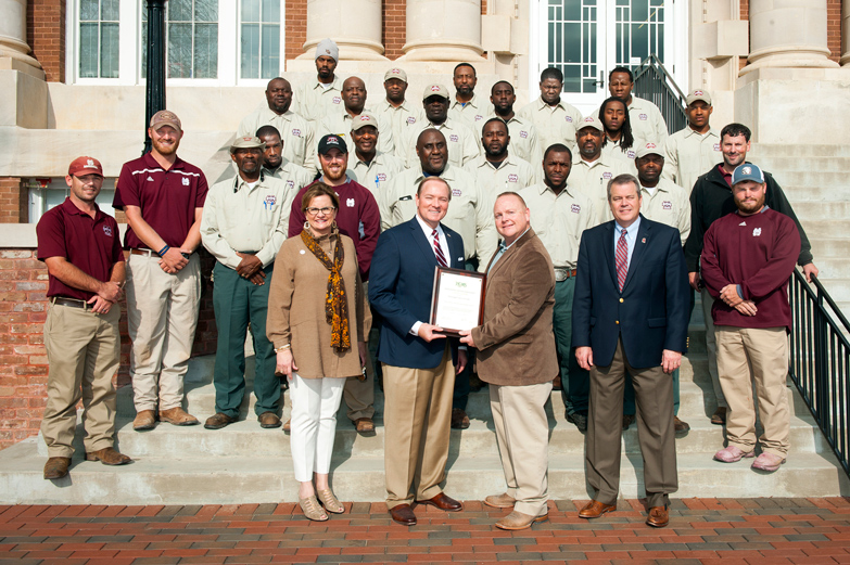 For the second year in a row, Mississippi State University has received a Green Star Award from the Professional Ground Management Society for “exceptional grounds maintenance” among U.S. universities and colleges. MSU Associate Director of Campus Landscape Bart Prather presented the award to MSU President Mark E. Keenum while Vice President of Campus Services Amy Tuck (front left) and Executive Director of Campus Services George Davis (front right) look on. The campus landscape crew includes: Front row, from left to right: Brandon Hardin and Terrell Brantley; Second row: Alex Miller, Willie Neely, Jordan Gleim, John Rice, Dashun Blair, Sammy Vaughn and Jim Bo Hearnsberger; third row: James Blair, Johnnie Turnipseed, Melvin Turnipseed and Shawn Higgins; fourth row: Randolph Calmes, Jimmy Rice, Frank Fulton, Jarmairo Carter, Katzman Rogers and Jamarius Tallie; back row: Anthony Johnson, Zeb Rice, Will Lawrence, Ivan Harris and Richard Nurse. Not pictured: Joey Boutwell, Victor Fulton, Edwin Lindsey and Perry Sellars. (Photo by Russ Houston)