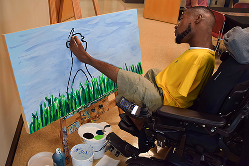 Kendrell Daniels paints with his feet at the 2023 T.K. Martin Center Express Yourself! Art Auction