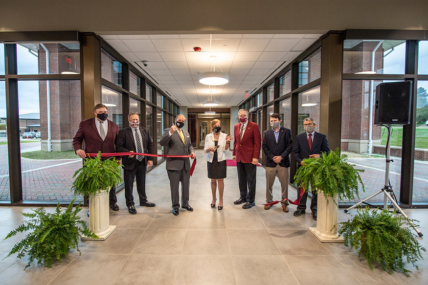 Seven MSU administrators and partners stand in a new building during a ribbon-cutting ceremony