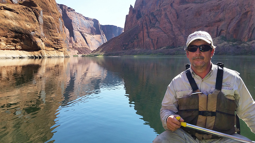 Wes Burger canoeing on the Colorado River with river and canyons in the background