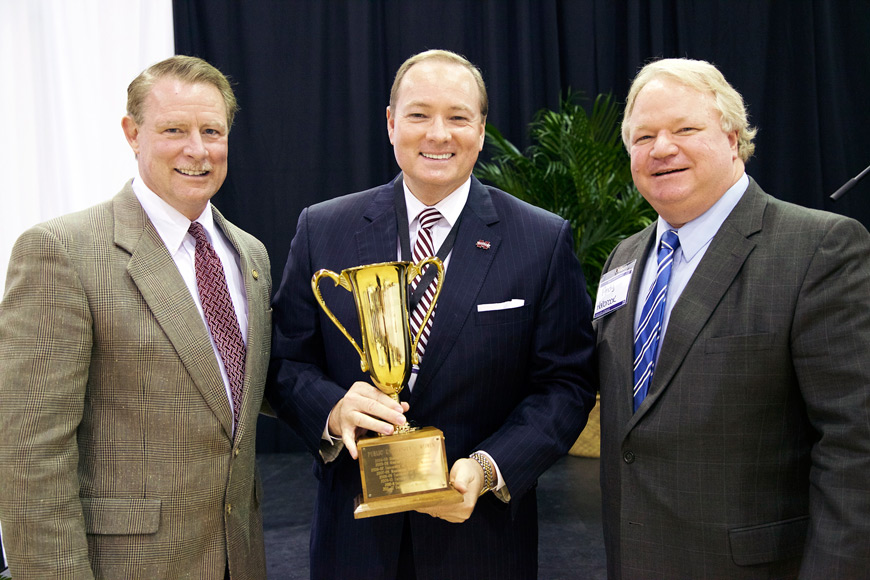 MSU President Mark E. Keenum, center, accepts a trophy during the Halbrook Awards ceremony from Commissioner of Higher Education Glenn Boyce, left, and Andy Halbrook, right.