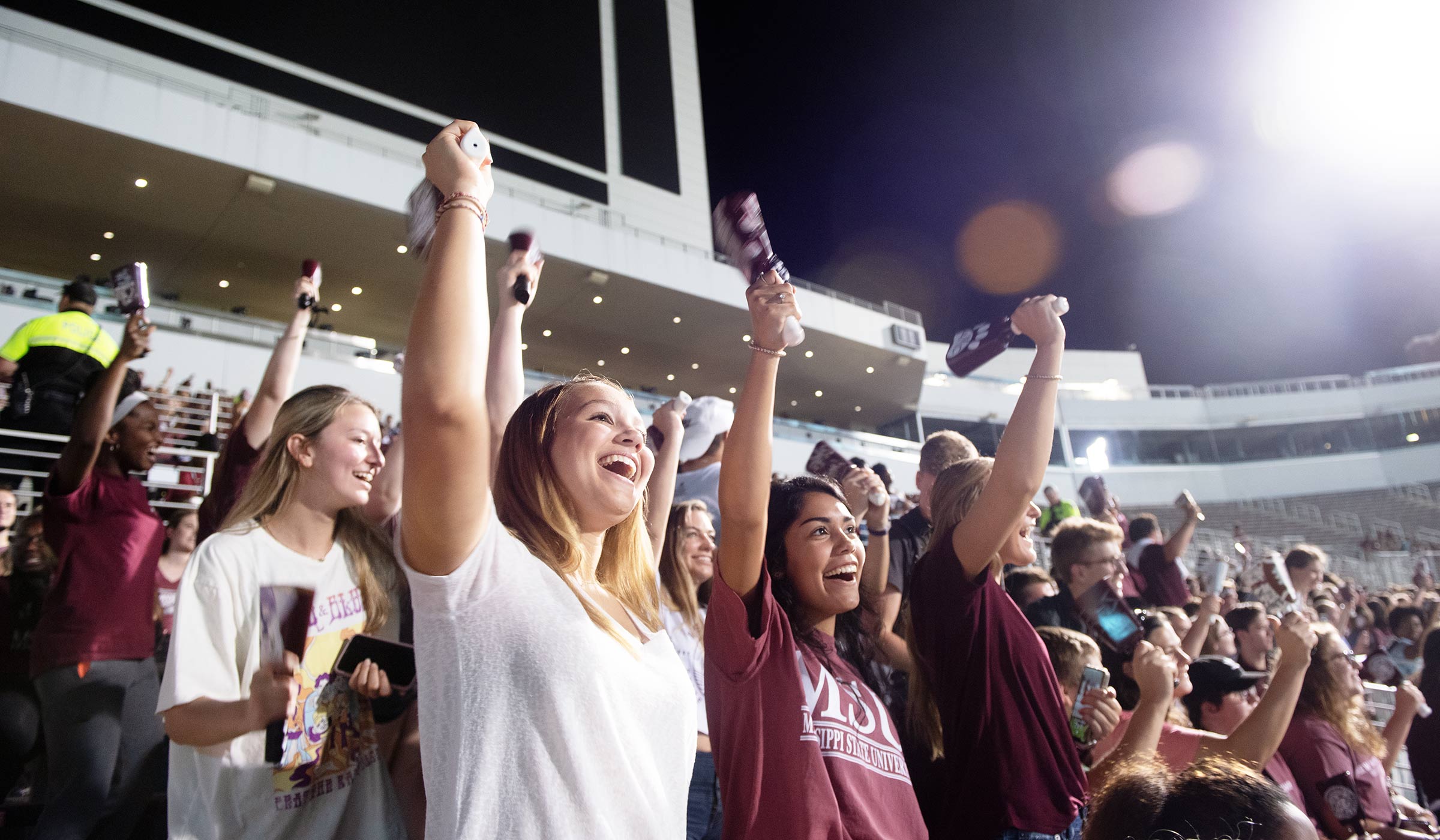 Students in white and maroon ringing cowbells and screaming in football stadium