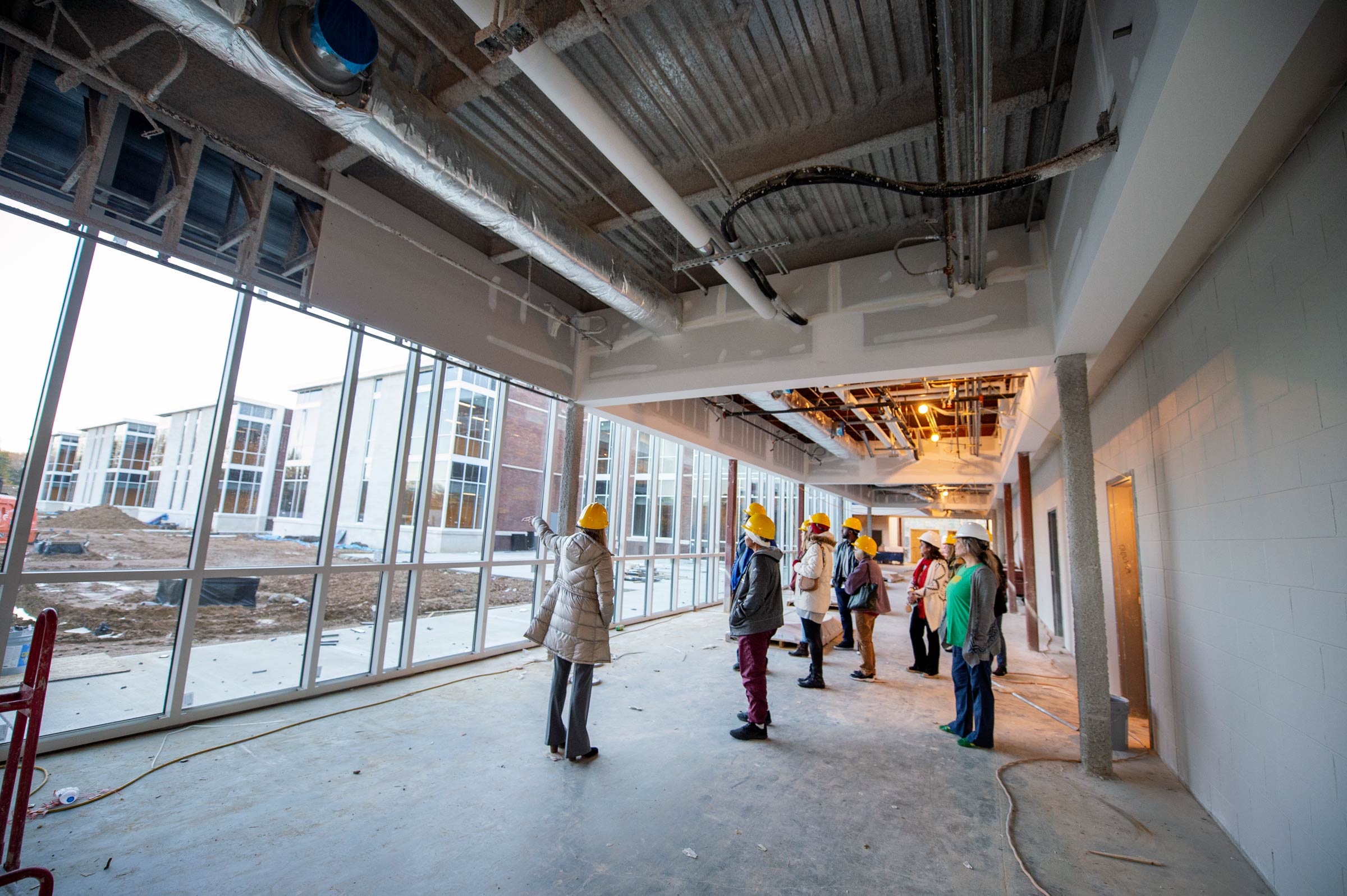 Principal Julie Kennedy leades a group of hard-hat clad teachers through the Parnership School construction site.