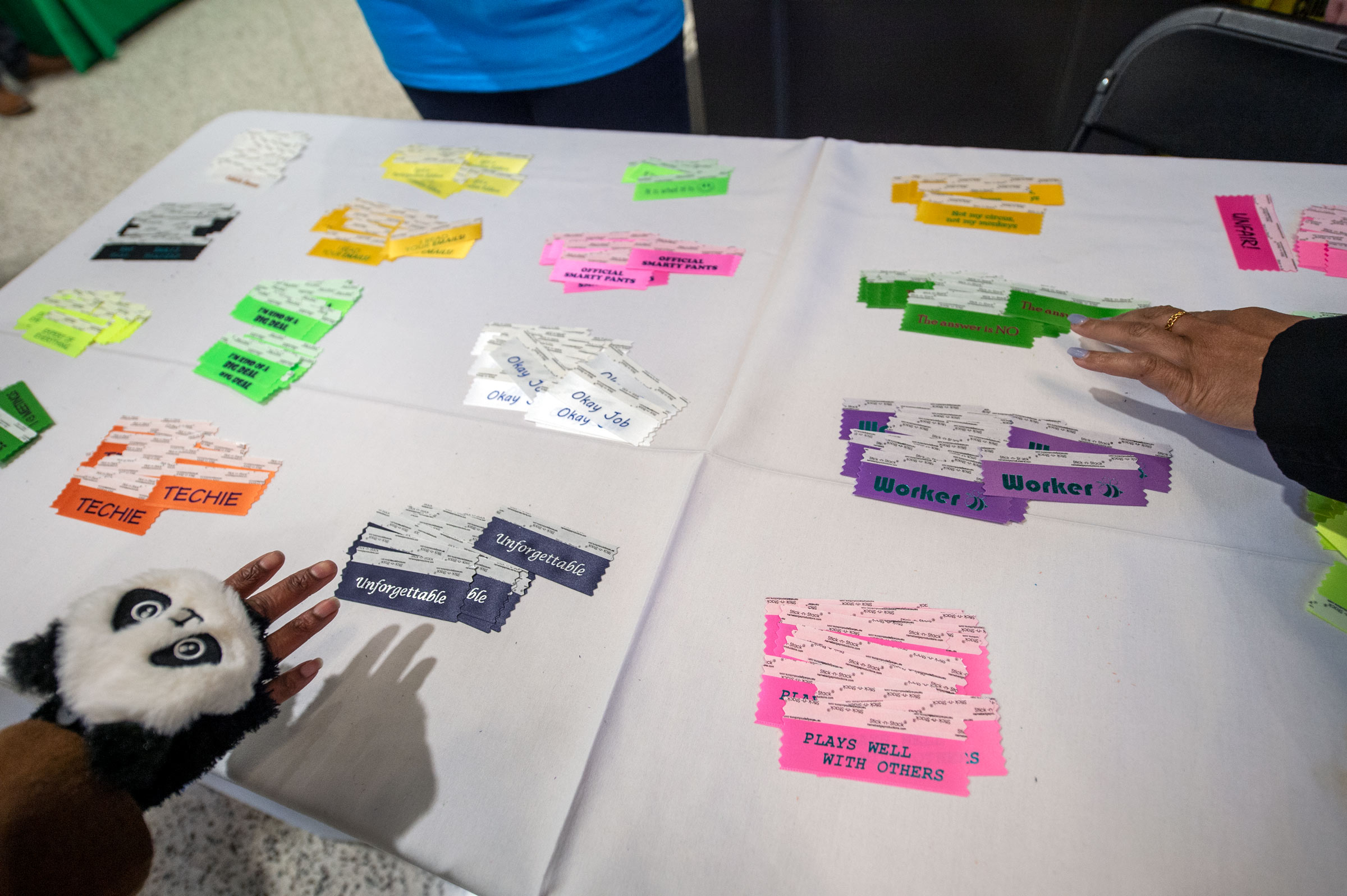 Employees hands reach for &quot;fun&quot; ribbons to add to their conference nametags.