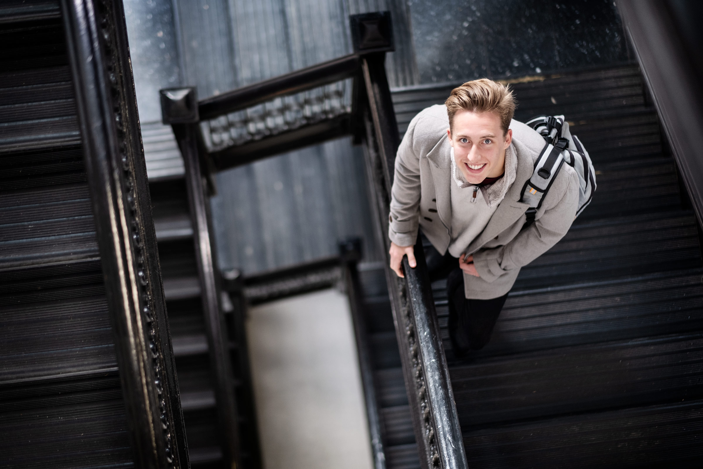 Phillipe Shicker, pictured on a staircase holding a backpack.