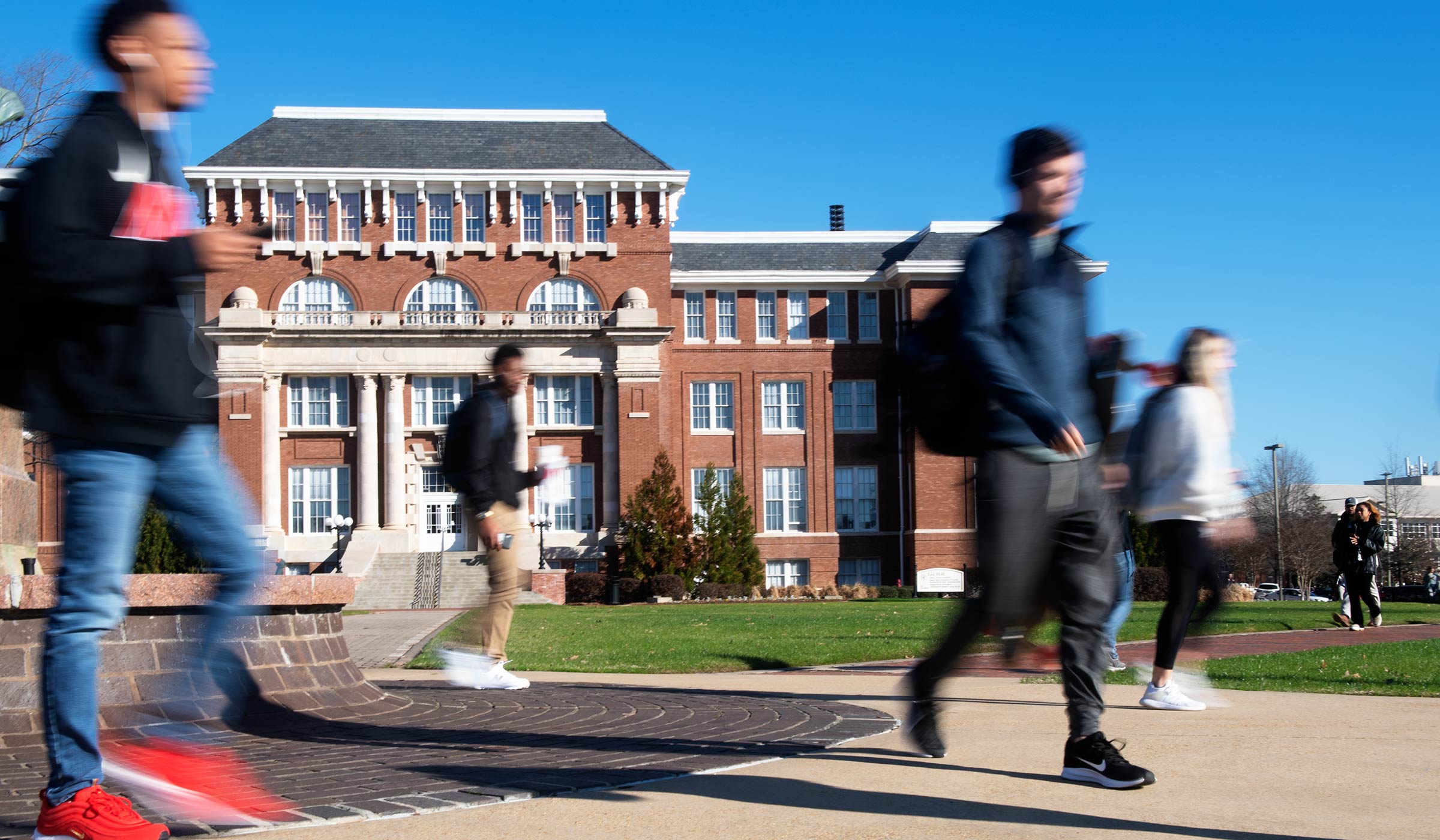 Students blurred in walking motion in front of red brick building