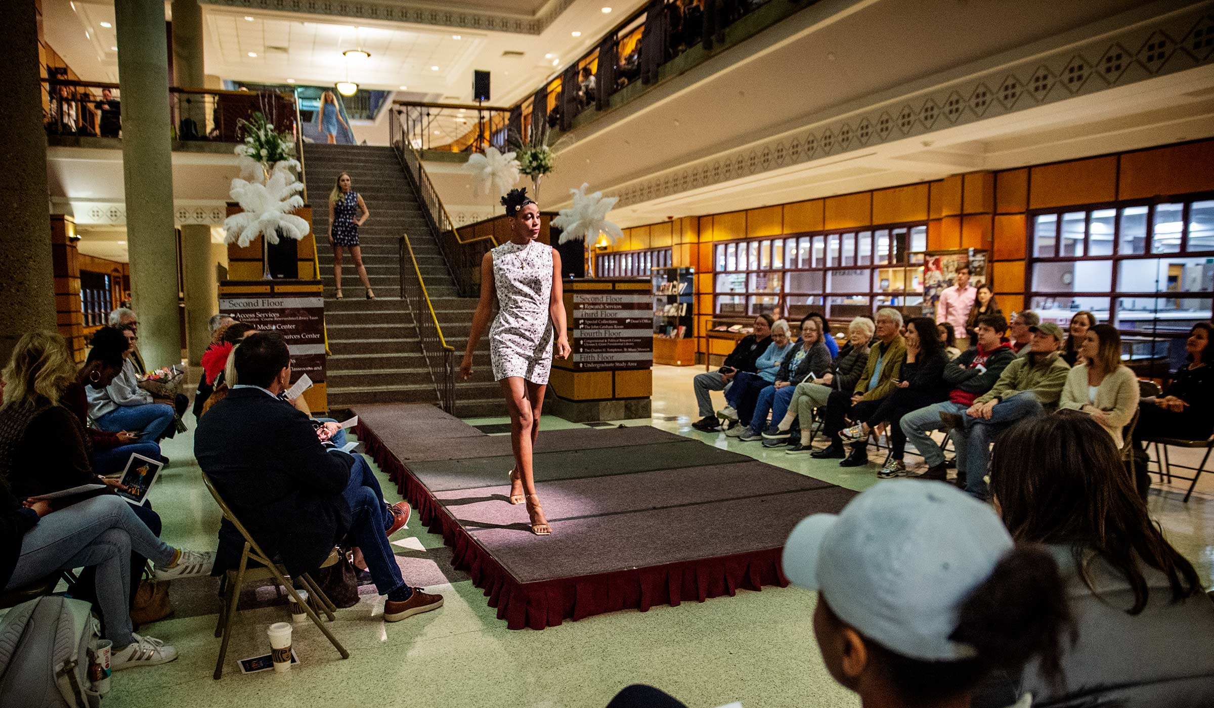 Lit by a spotlight, models in 1920s clothes walk down the Library stairs and work the runway at the base surrounded by the seated audience.