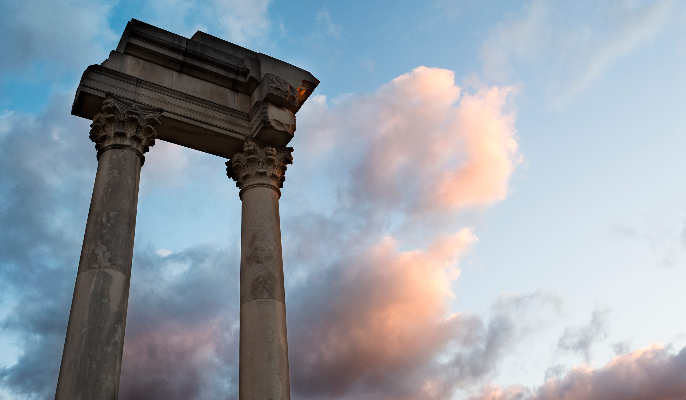 Set of Corinthian columns with clouds showing sunrise colors in background