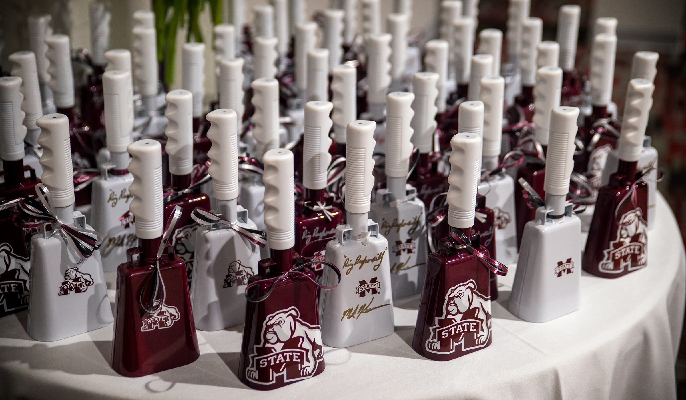 A sea of maroon and white cowbells signed by President Keenum cover a round banquet table.
