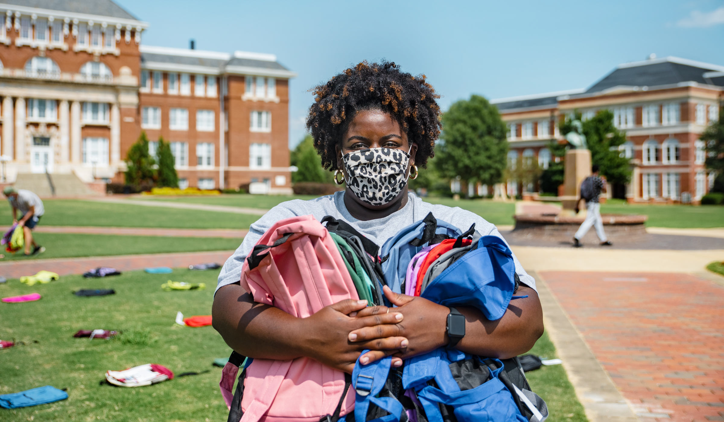 MSU graduate assistant Gillian Goodloe holds suicide awareness backpacks on the Drill Field, while wearing a mask.