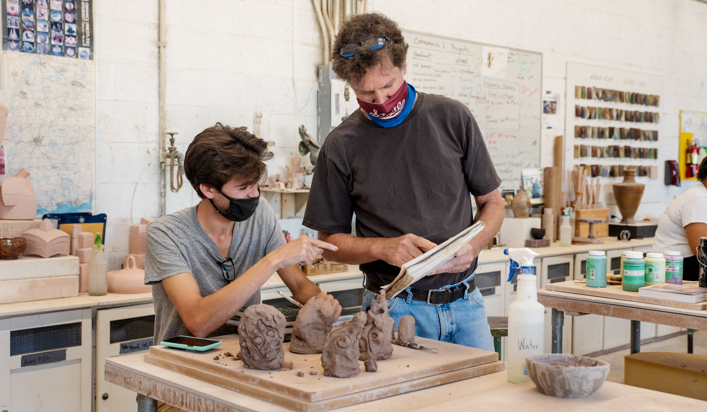 Professor Robert Long helps student Joseph MacGown with his clay project in the Howell Hall pottery studio.