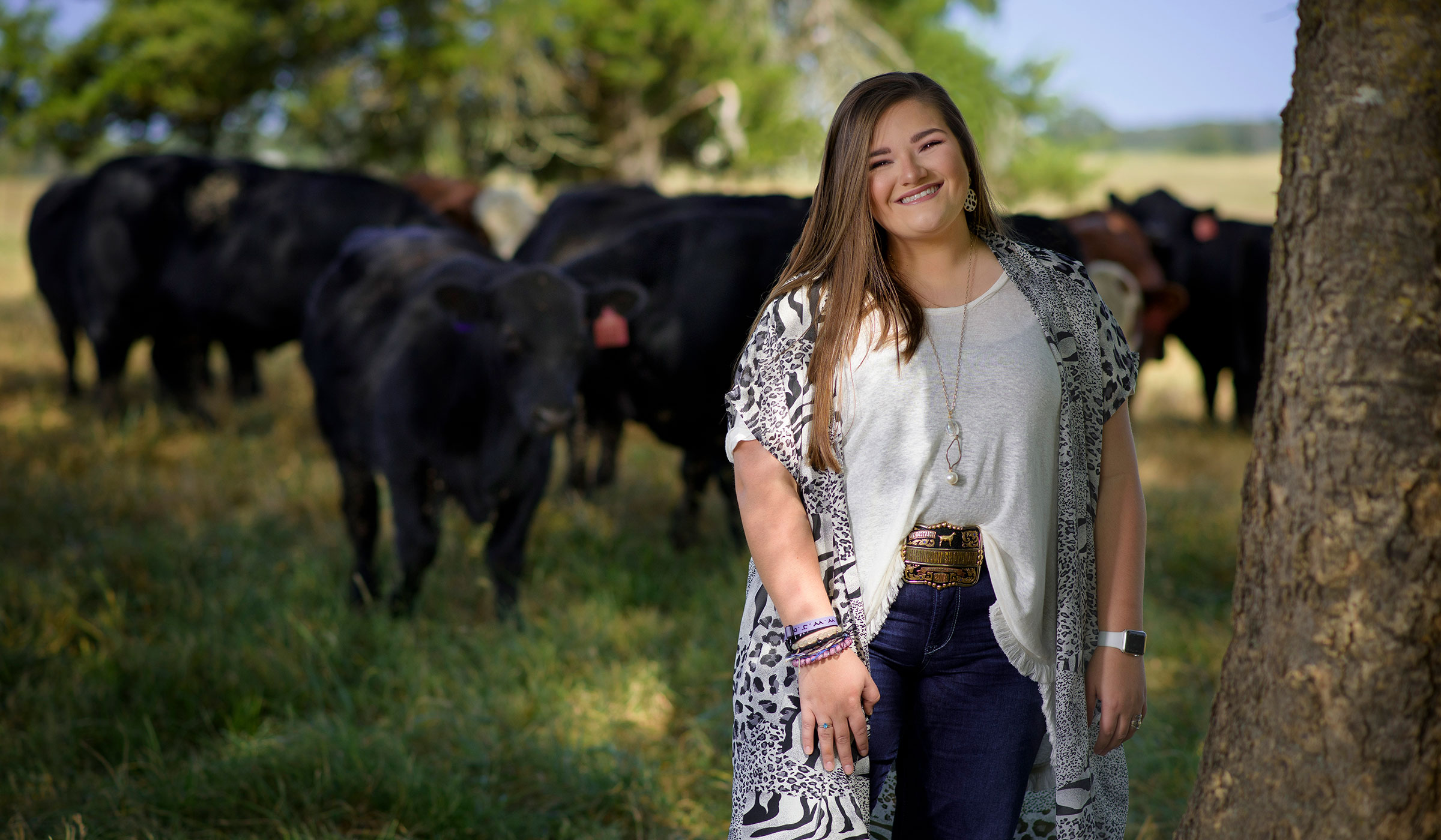 Mikayla Shelton stands outside with black cattle in the background
