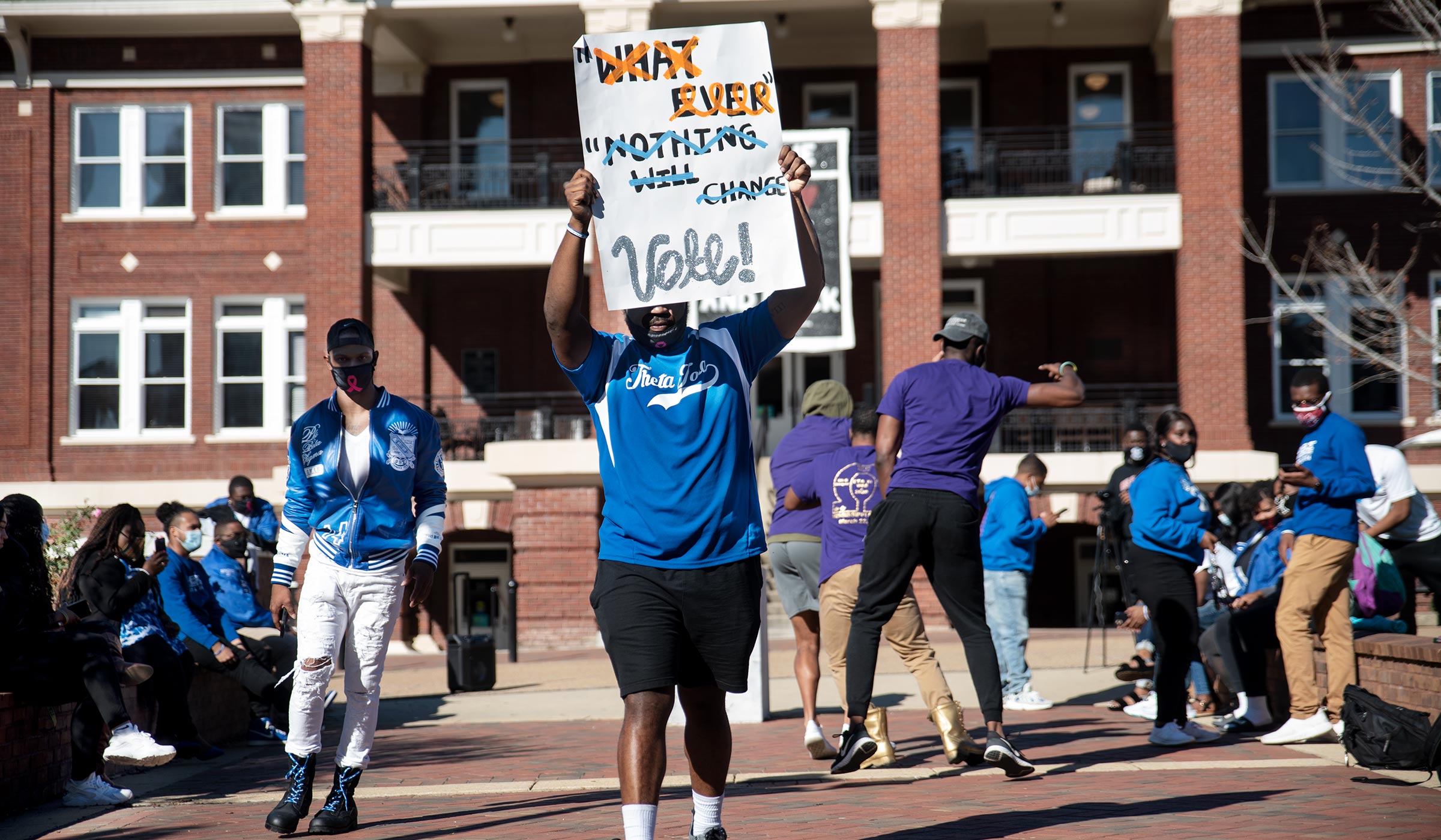 To help promote Election Day voting, fraternity members &quot;stroll off&quot; in front of the YMCA building holding signs encouraging voting.