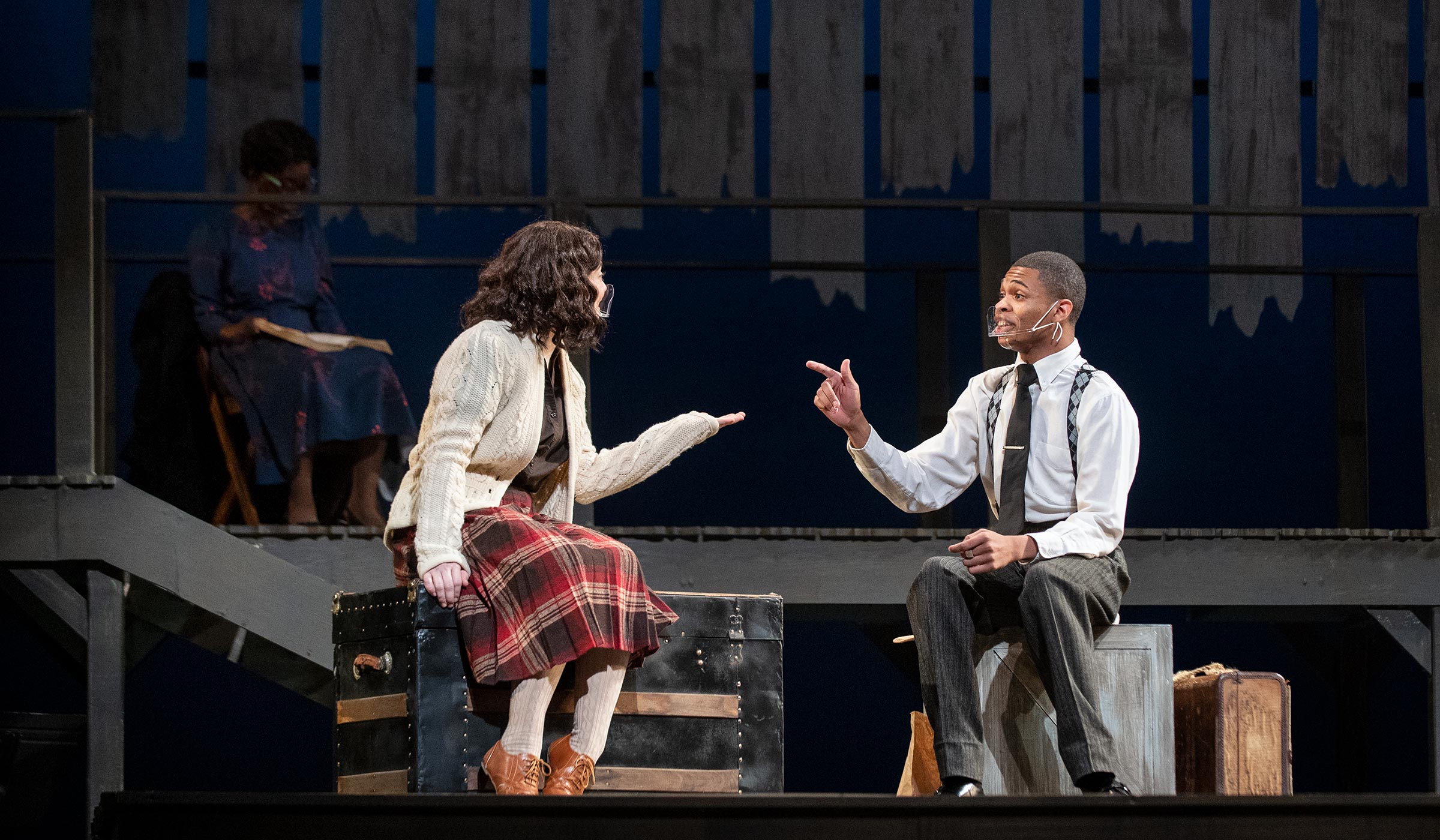 Student actors Allyn Hackman and Cameron Mayers speak while seated on the stage, while playing Anne Franks and Emmett Till, respectively.