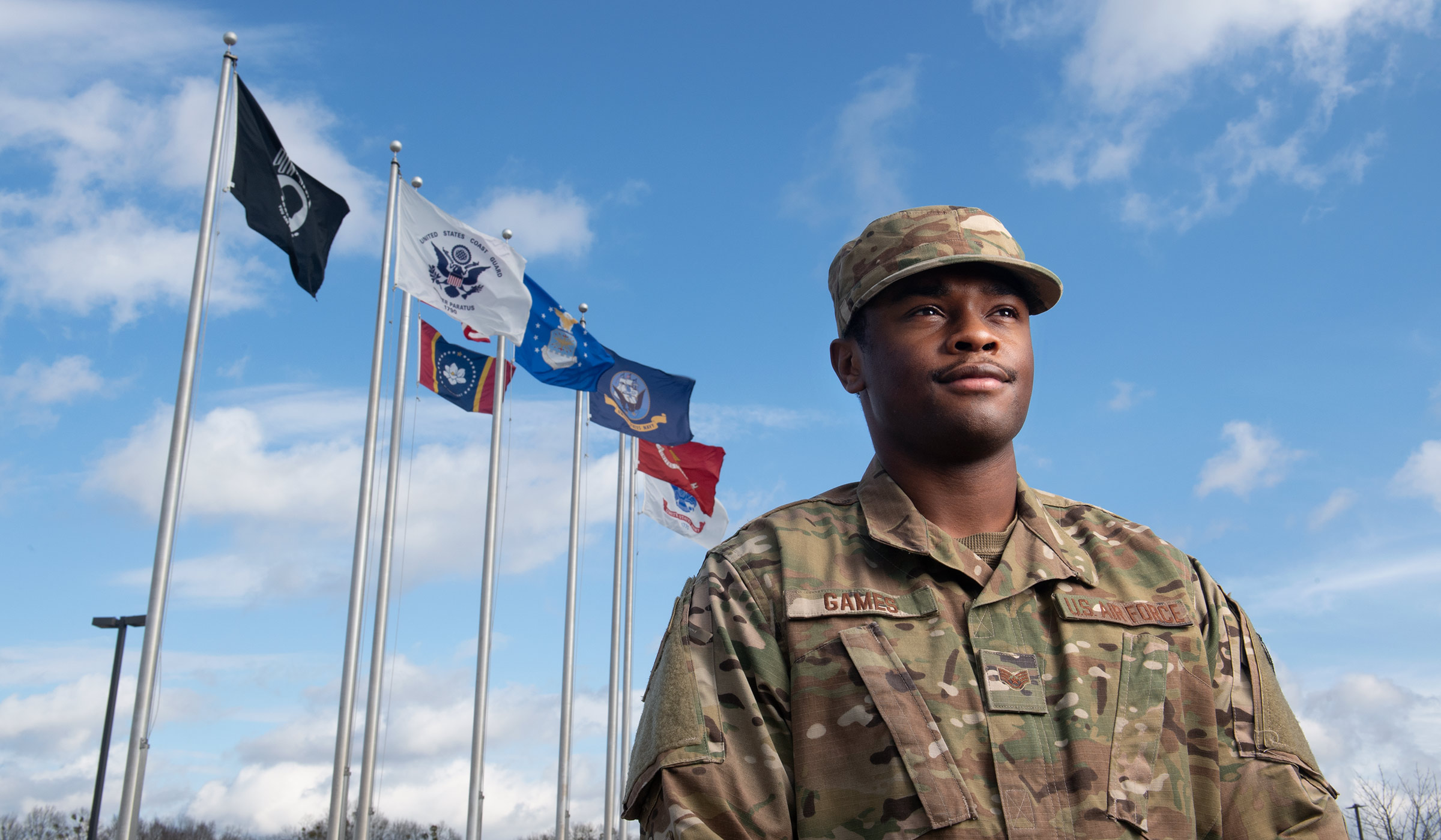 Patrick Games, pictured in his Air Force uniform in front of U.S. military flags.