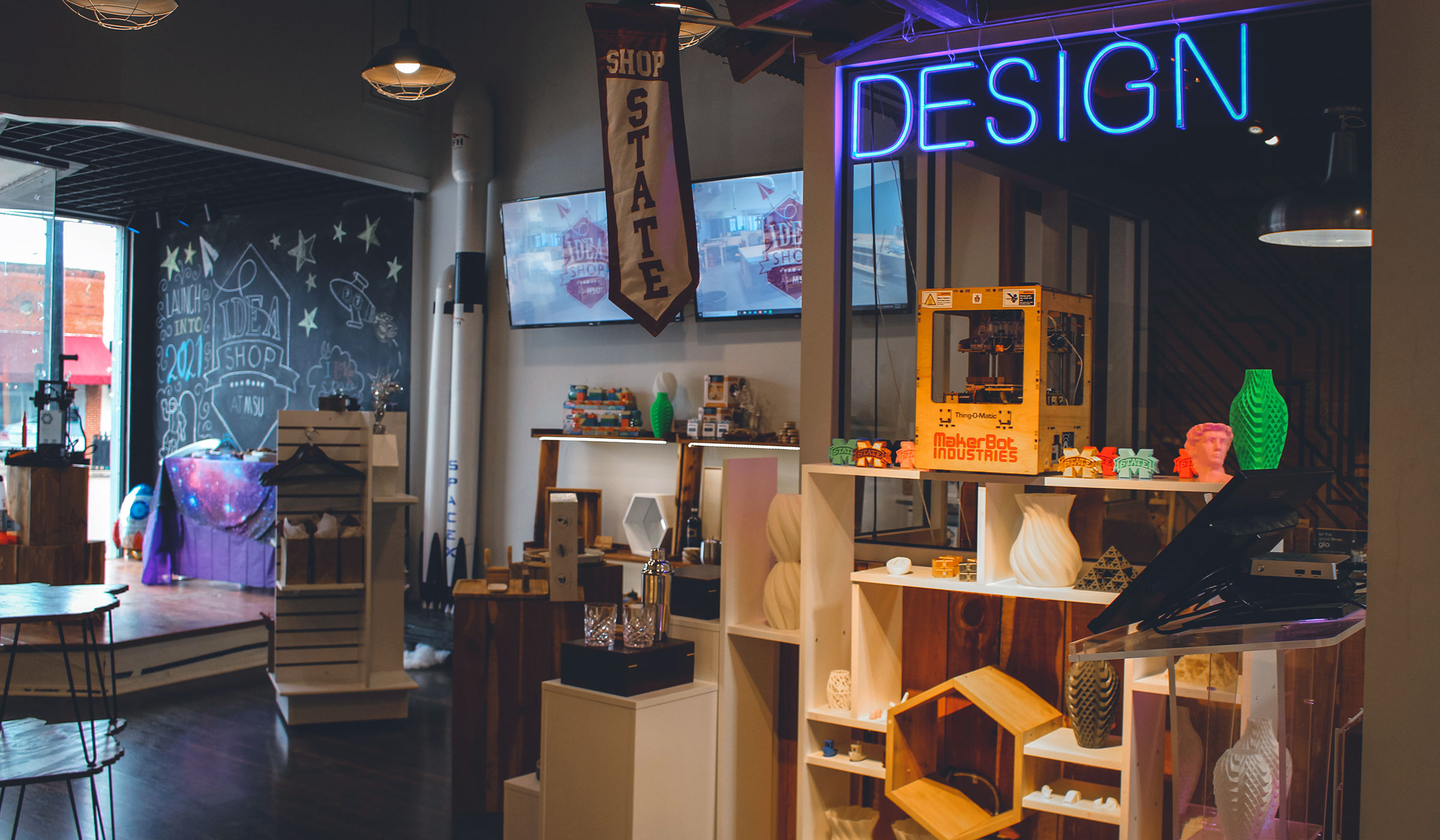 Room with neon design sign and STEM oriented projects and 3D printed objects on shelves