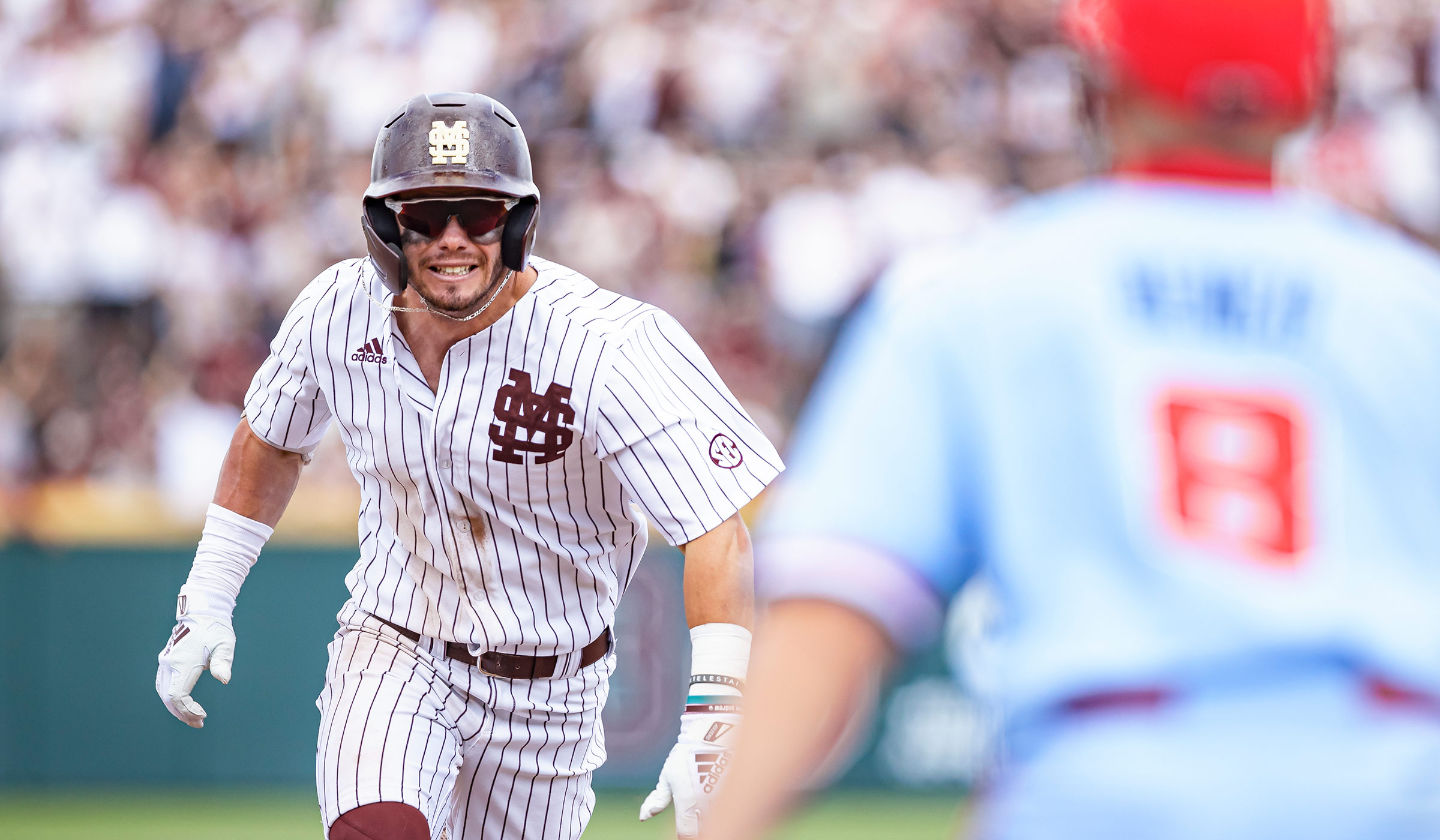 Man in maroon helmet and maroon and white pinstripe baseball uniform running