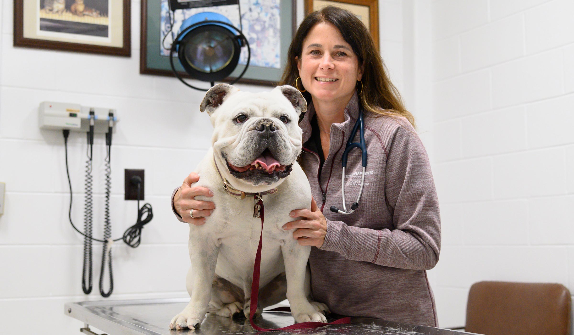 Juli Gunter, pictured with a dog on a veterinary examining table.