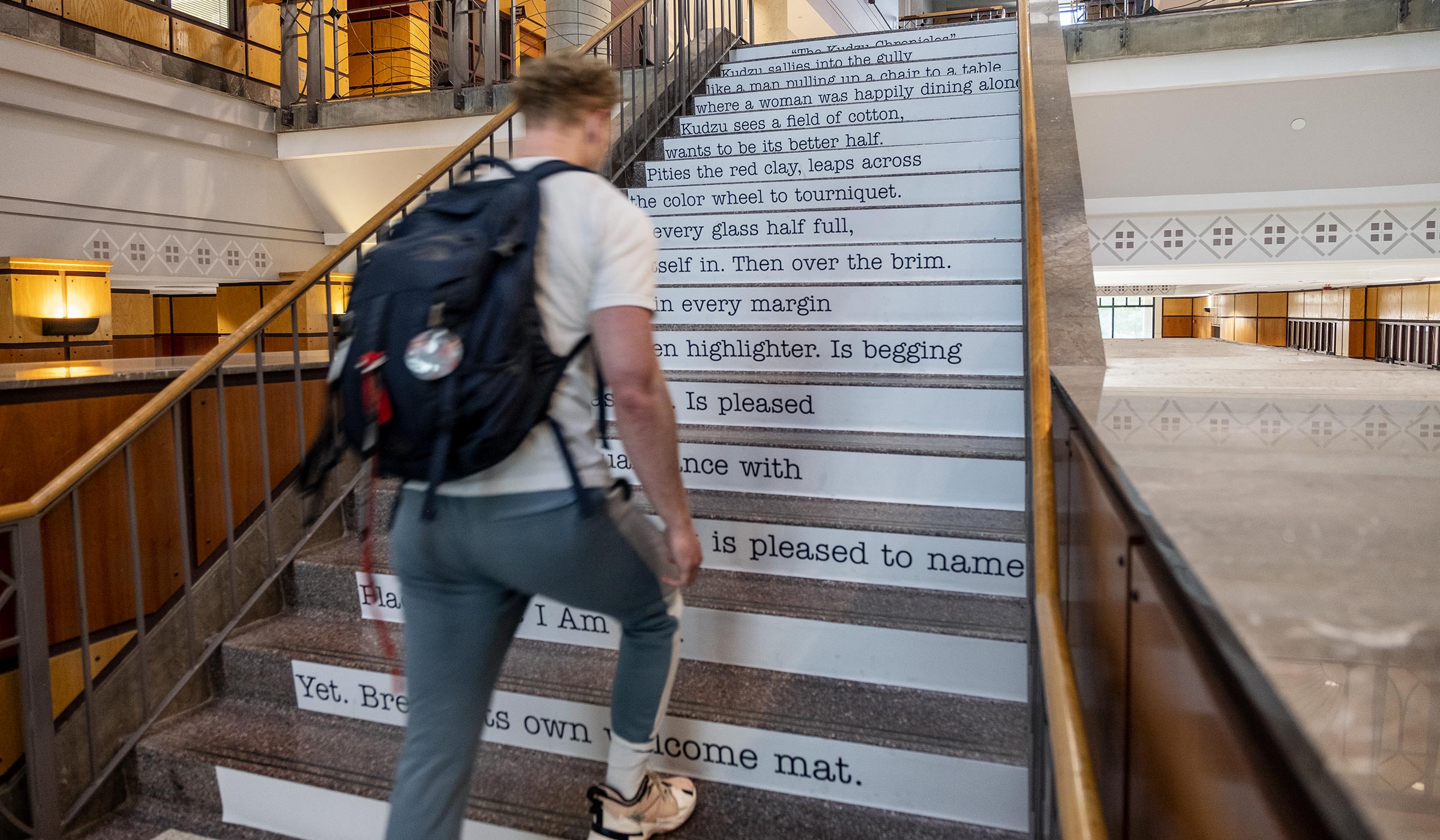 Recent alumni James Ladd Garner climbs poetry covered stairs at Mitchell Memorial Library.