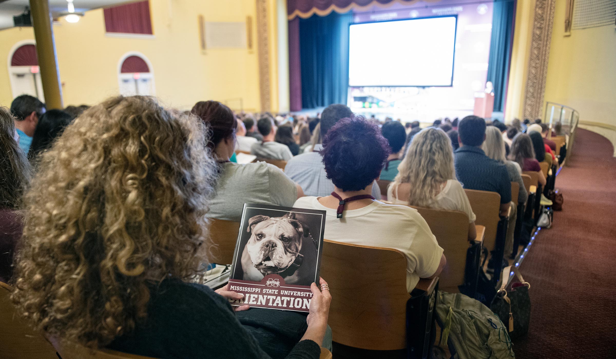 With Bettersworth Auditorium filled with incoming Honors Freshmen and their parents, an attendee holds this year&#039;s Orientation brochure with bulldog Jak on the cover.