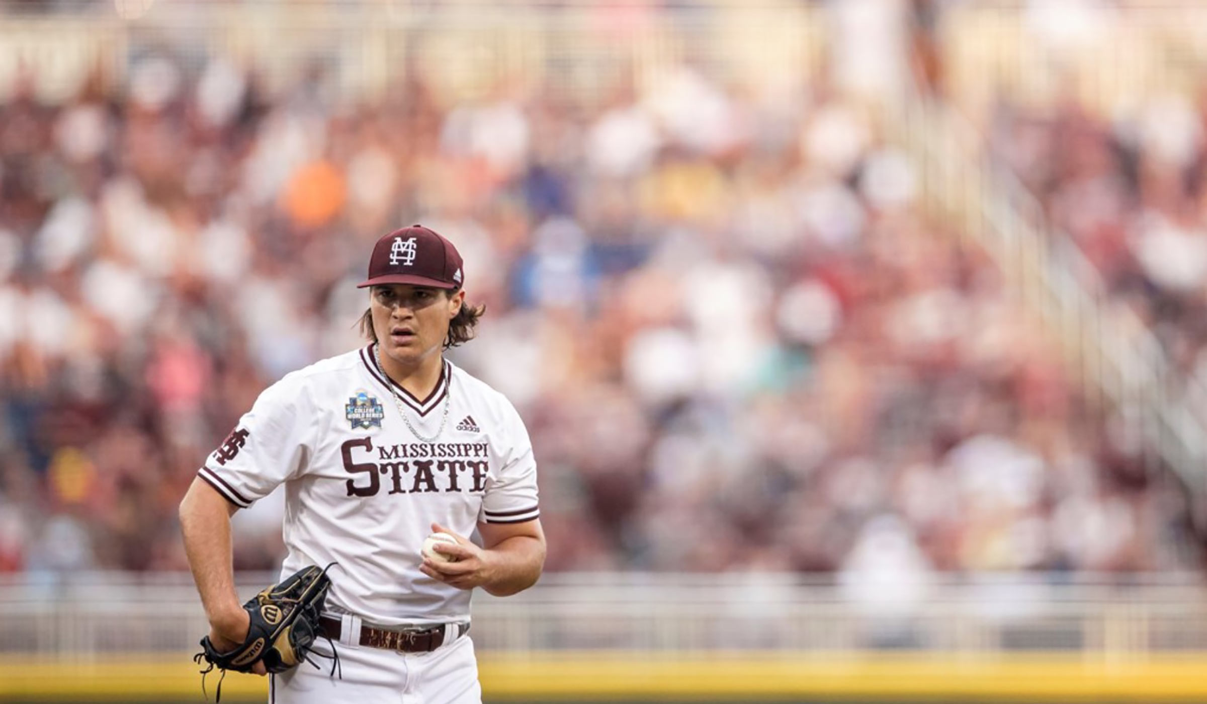 Guy in white baseball uniform and maroon cap holding baseball in left hand