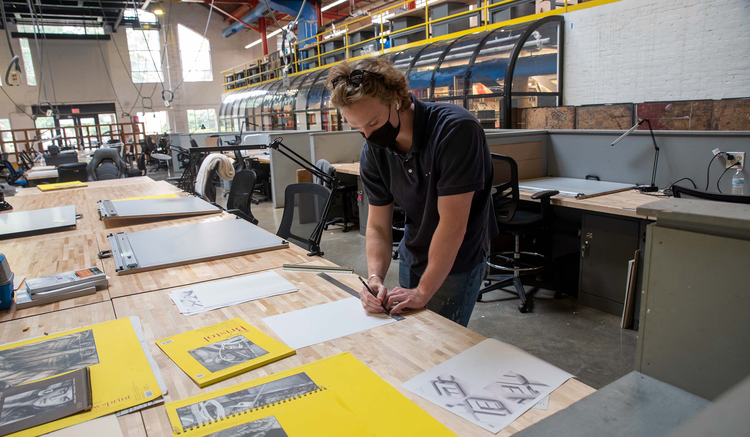 Male student in dark polo shirt working on architectural drawings