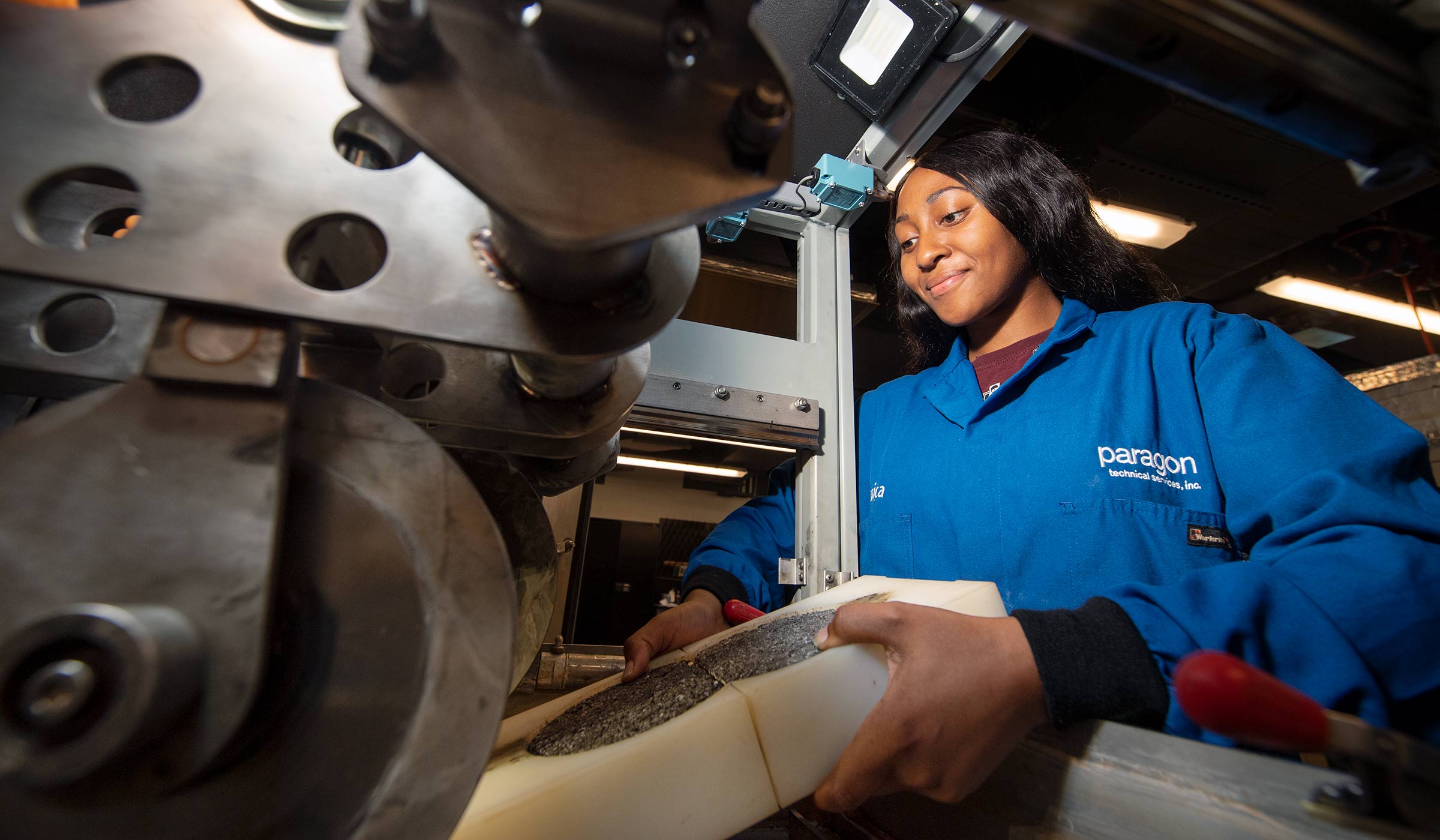 Female student in blue lab coat adding a sample to machine