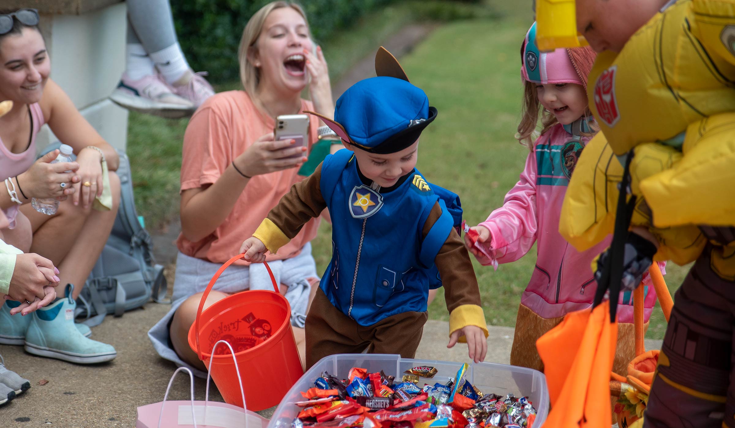 Kids in paw patrol and transformer costumes getting candy out of bin