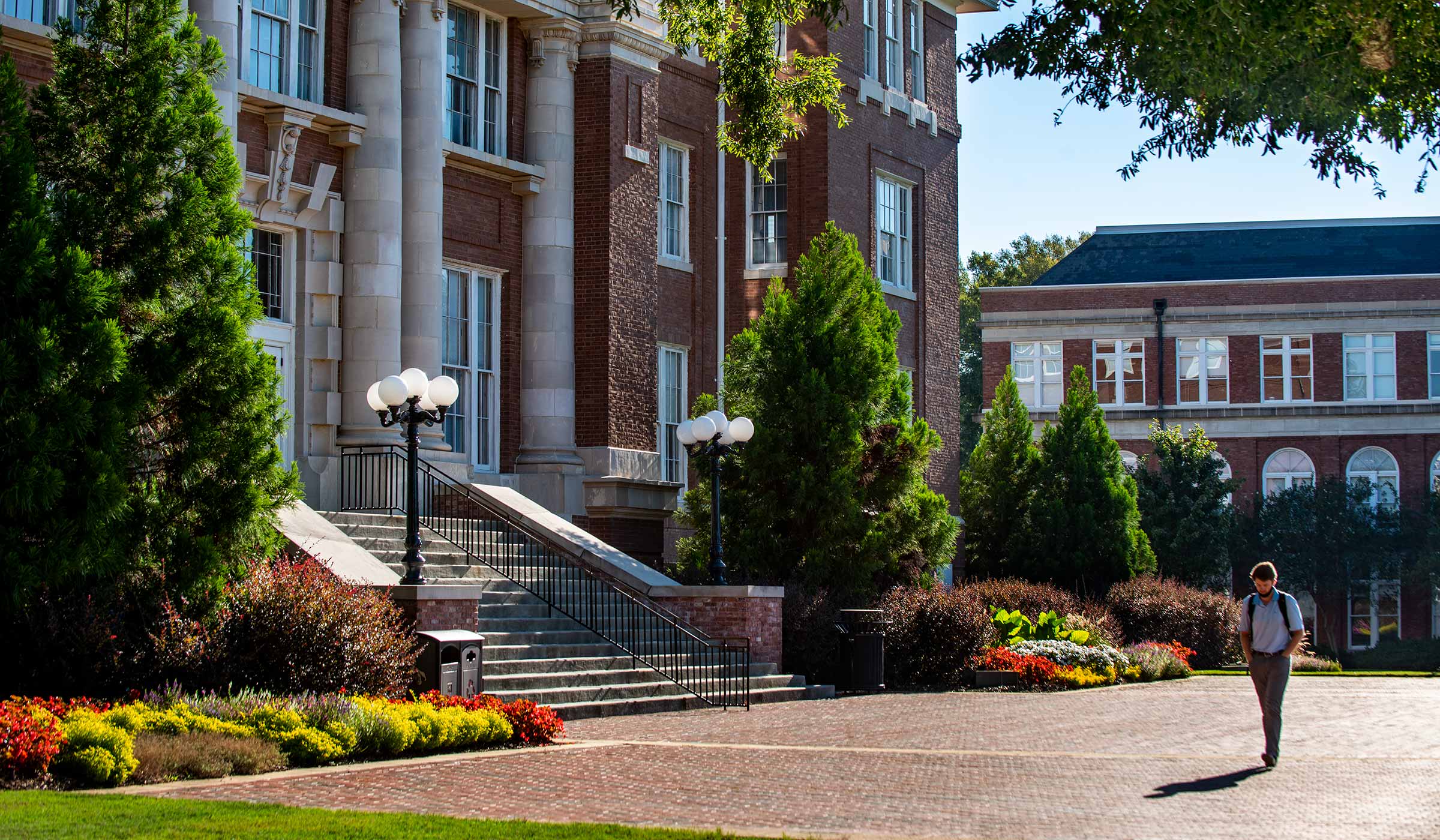 Student walking in front of Lee Hall in early morning